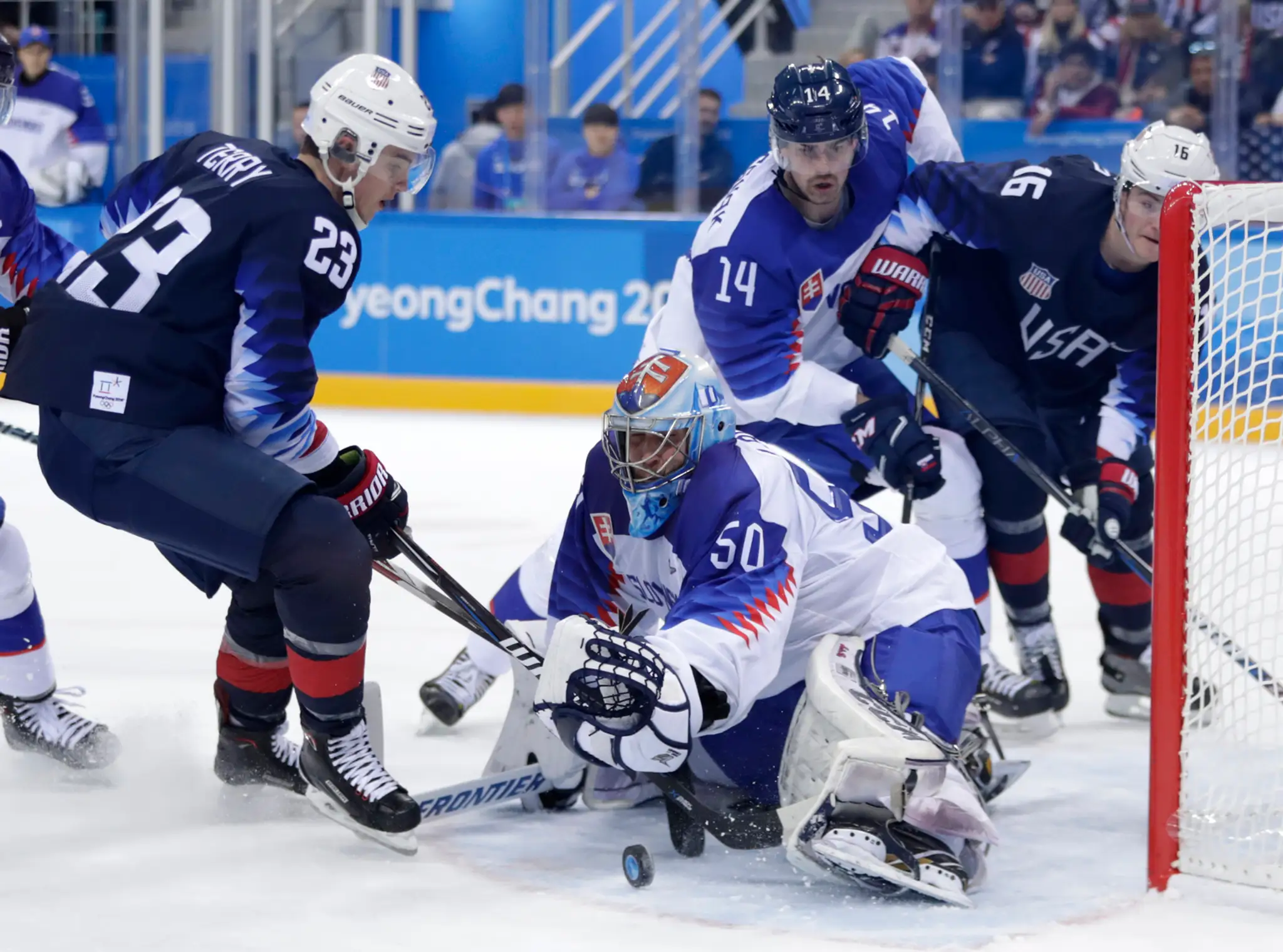 Ryan Zapolski z USA chytá puk pred Michalom Krištofom v zápase na ZOH 2018.