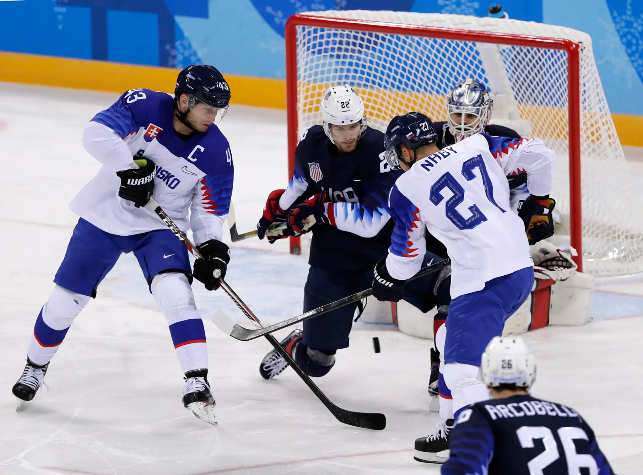 Gólman Slovenska Ján Laco chytá puk pred Chadom Kolarikom z USA v zápase na ZOH 2018.