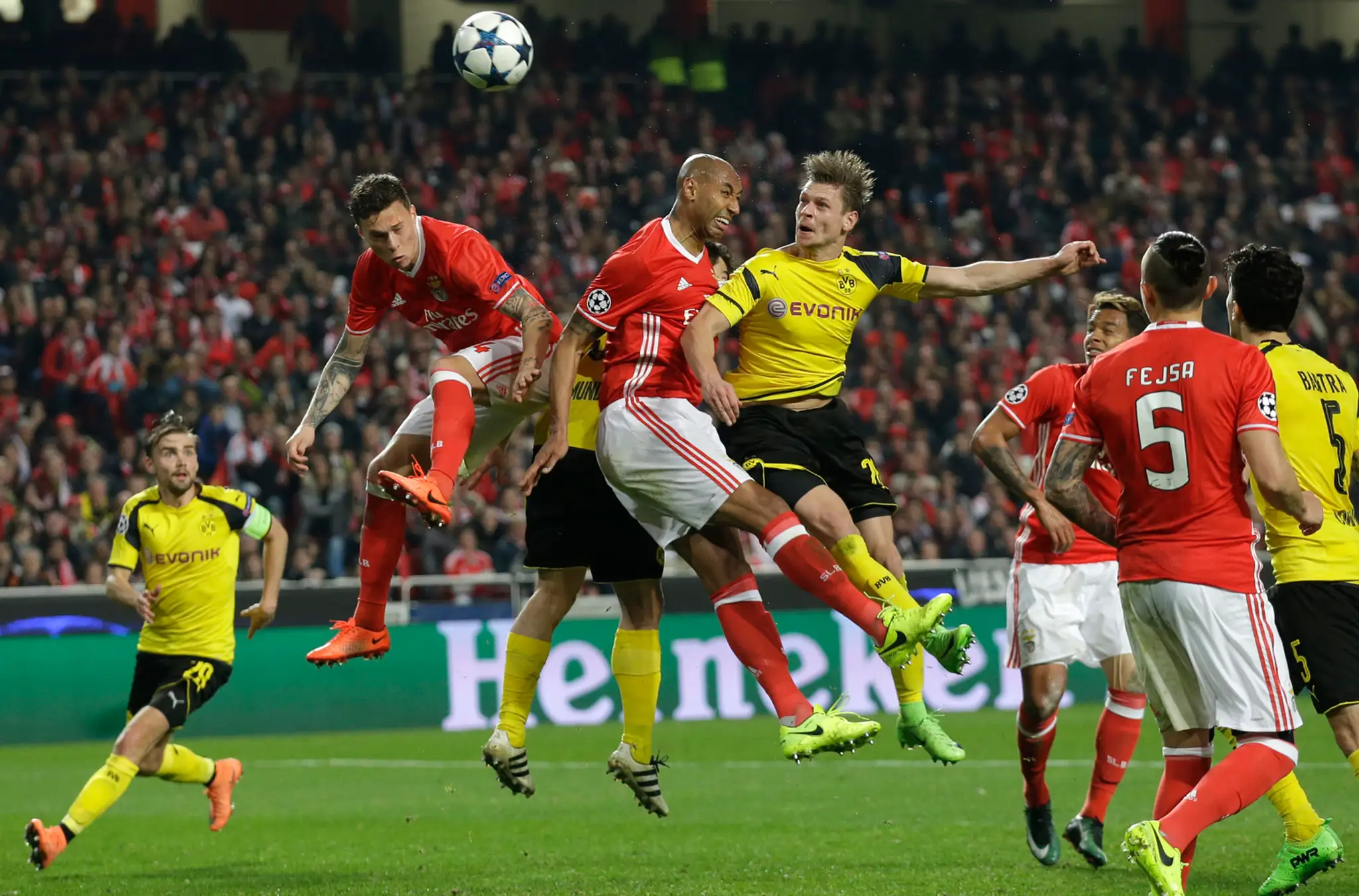 Lukasz Piszczek z Dortmundu (vpravo) hlavičkuje v osemfinále LM do lopty, takisto aj dvojica z Benficy - vľavo Luisao a Victor L