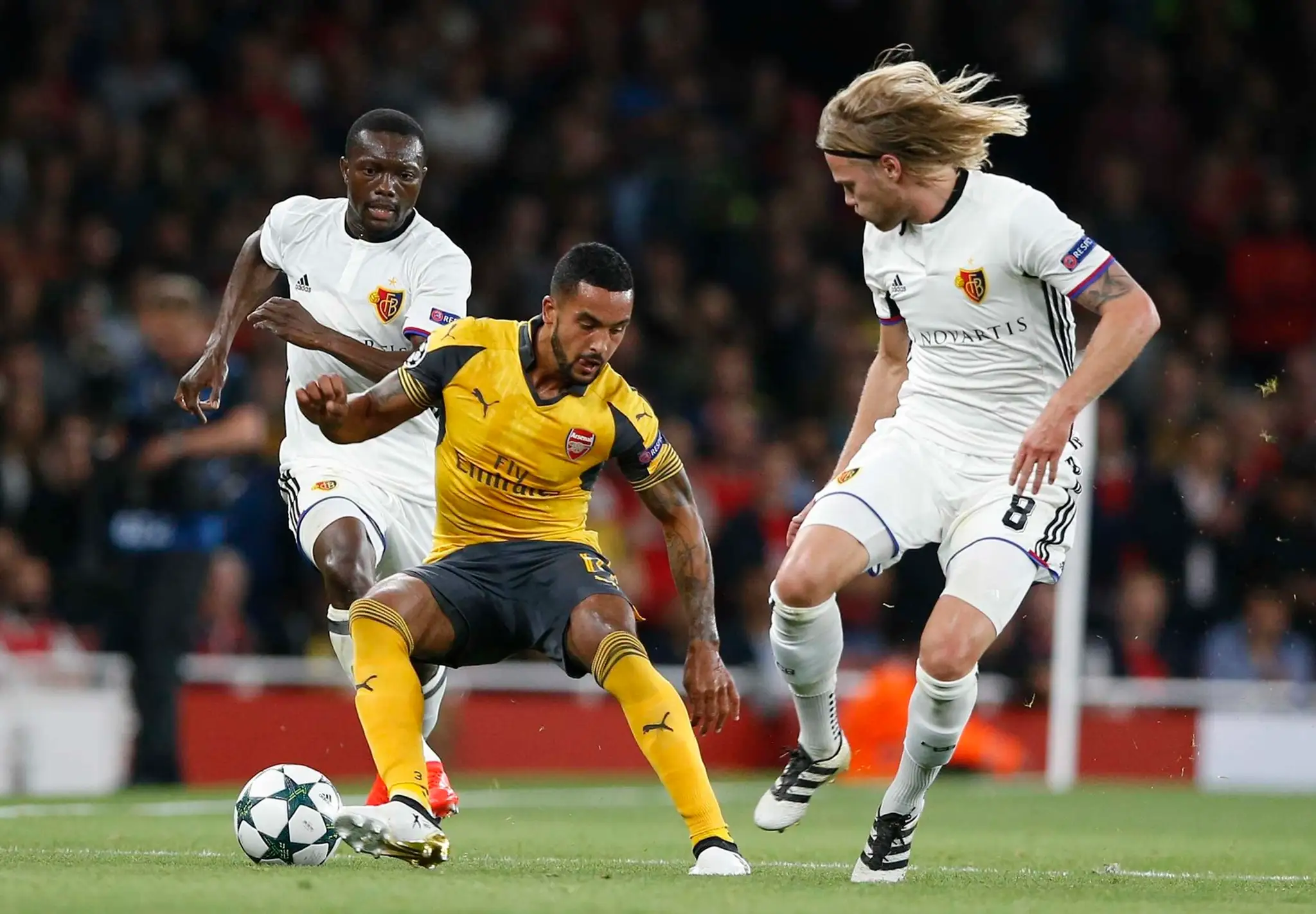 Krídelník Arsenalu Theo Walcott v súboji o loptu proti Birkirovi Bjarnasonovi z Bazileja v dueli LM.