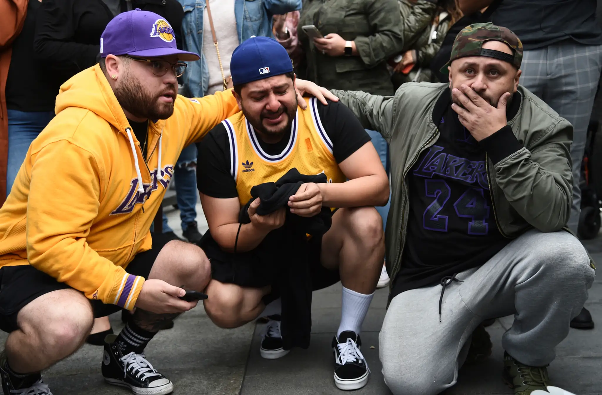 Fanúšik Los Angeles kľačí pred múrom s podobizňou Kobeyho Bryanta.
