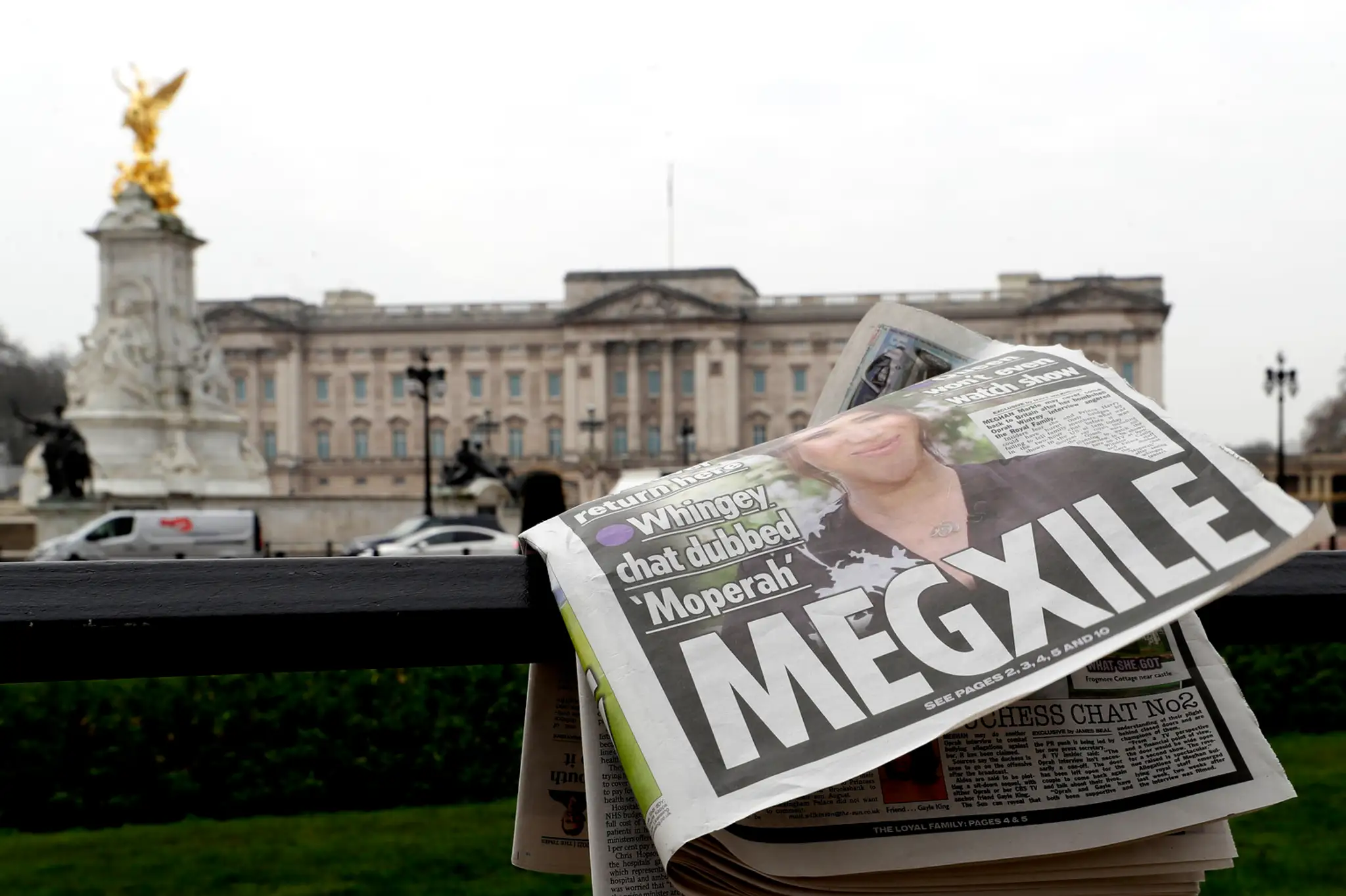 Titulka s Meghan, v pozadí Buckinghamský palác.