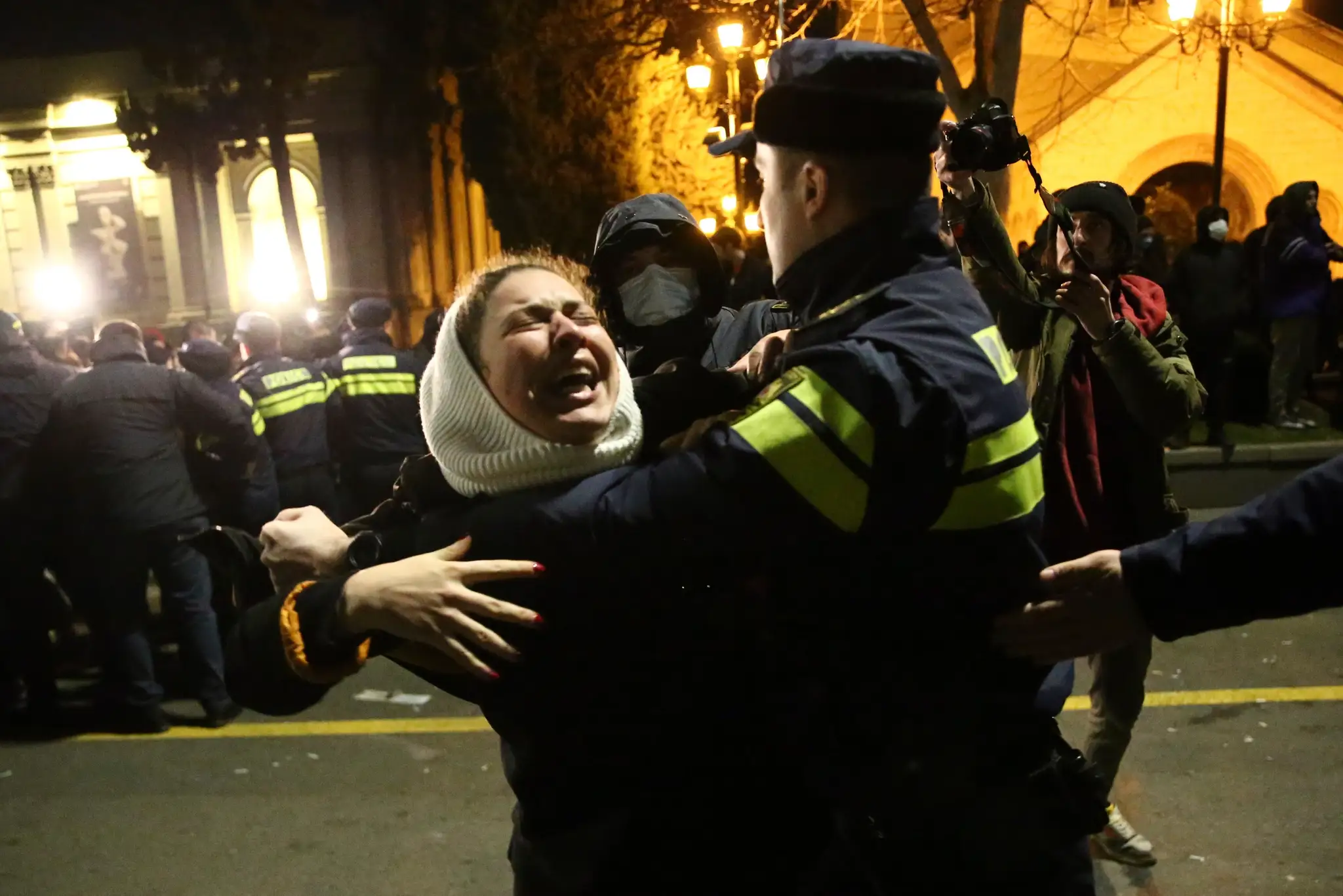 Policajt zatýka demonštrantku počas protestu pred budovou parlamentu v Tbilisi.