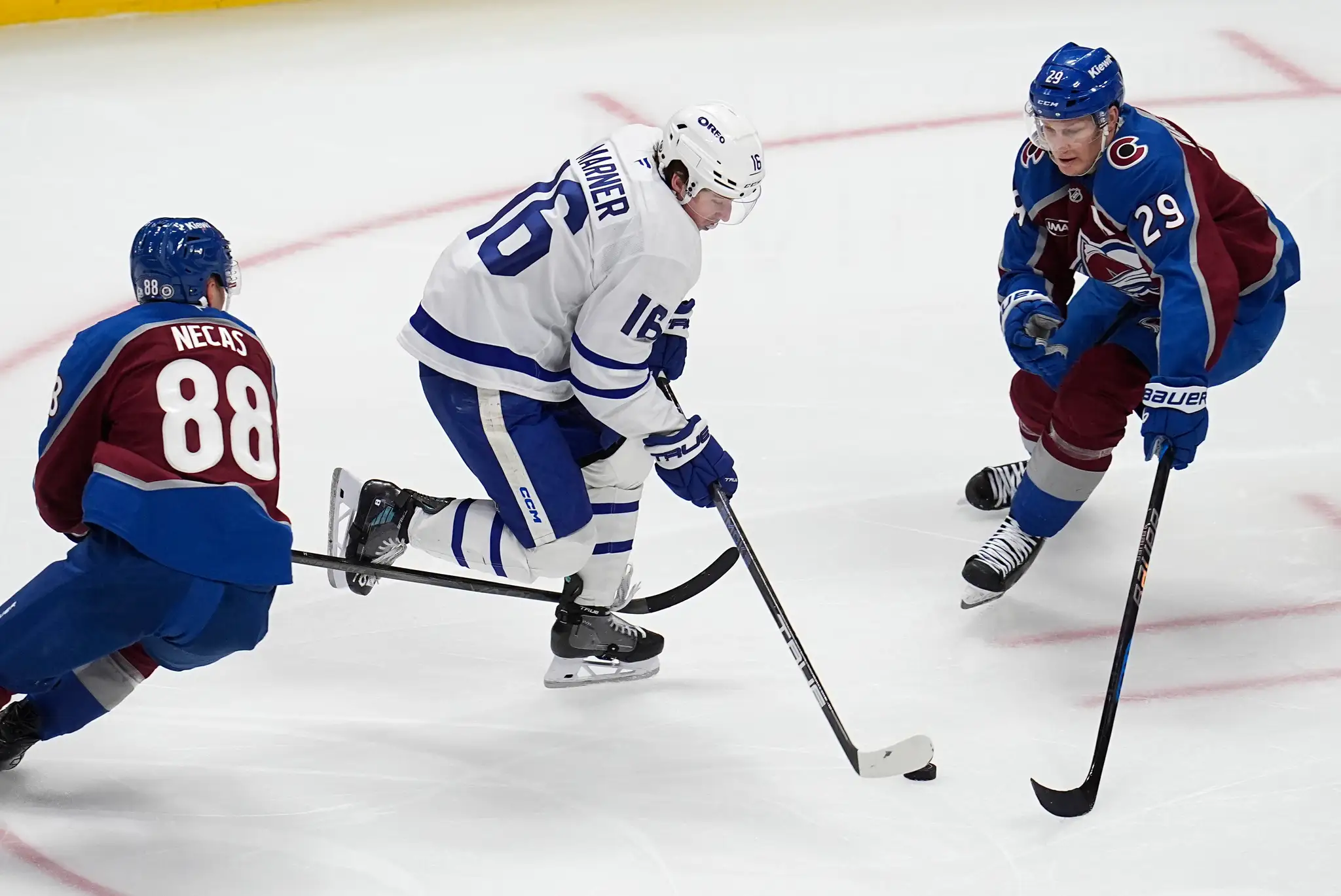 Na snímke hokejista Toronta Mitch Marner (uprostred), hráči Colorada Martin Nečas (vľavo) a Nathan MacKinnon (vpravo).