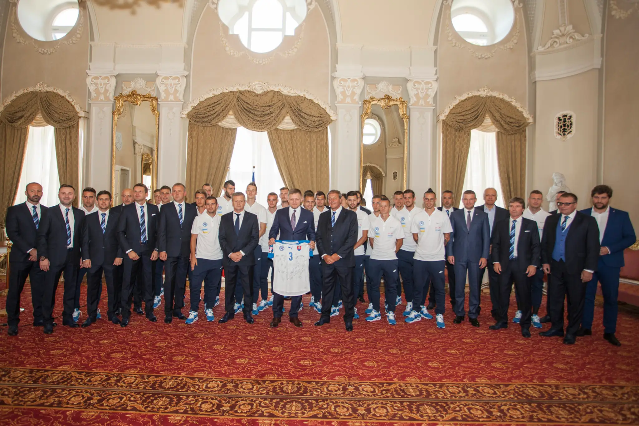 Predseda vlády Robert Fico (uprostred) drží dres slovenskej futbalovej reprezentácie s podpismi počas prijatia A reprezentačného