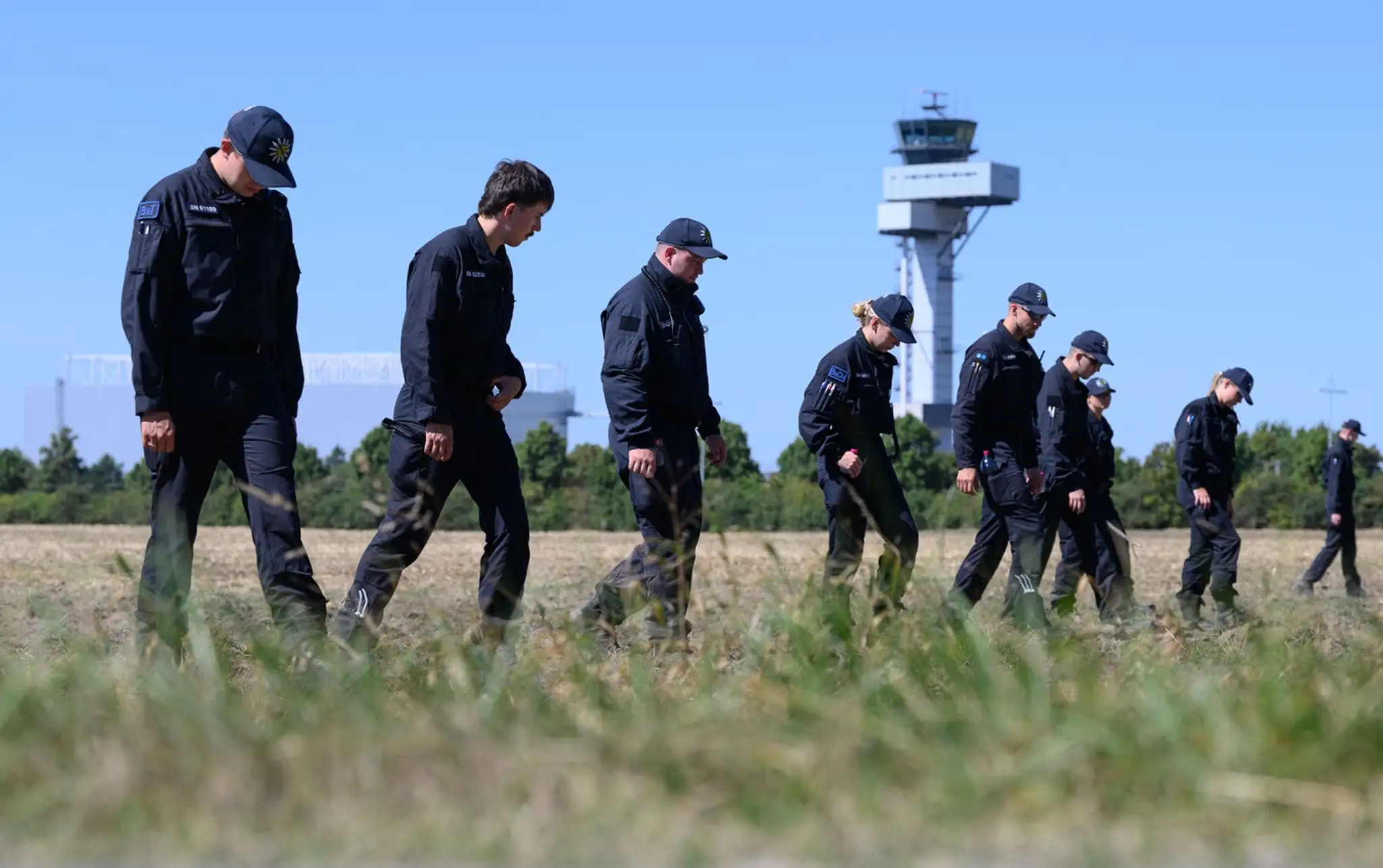 Policajti prehľadávajú pole na letisku Lipsko/Halle v snahe nájsť dôkazy.
