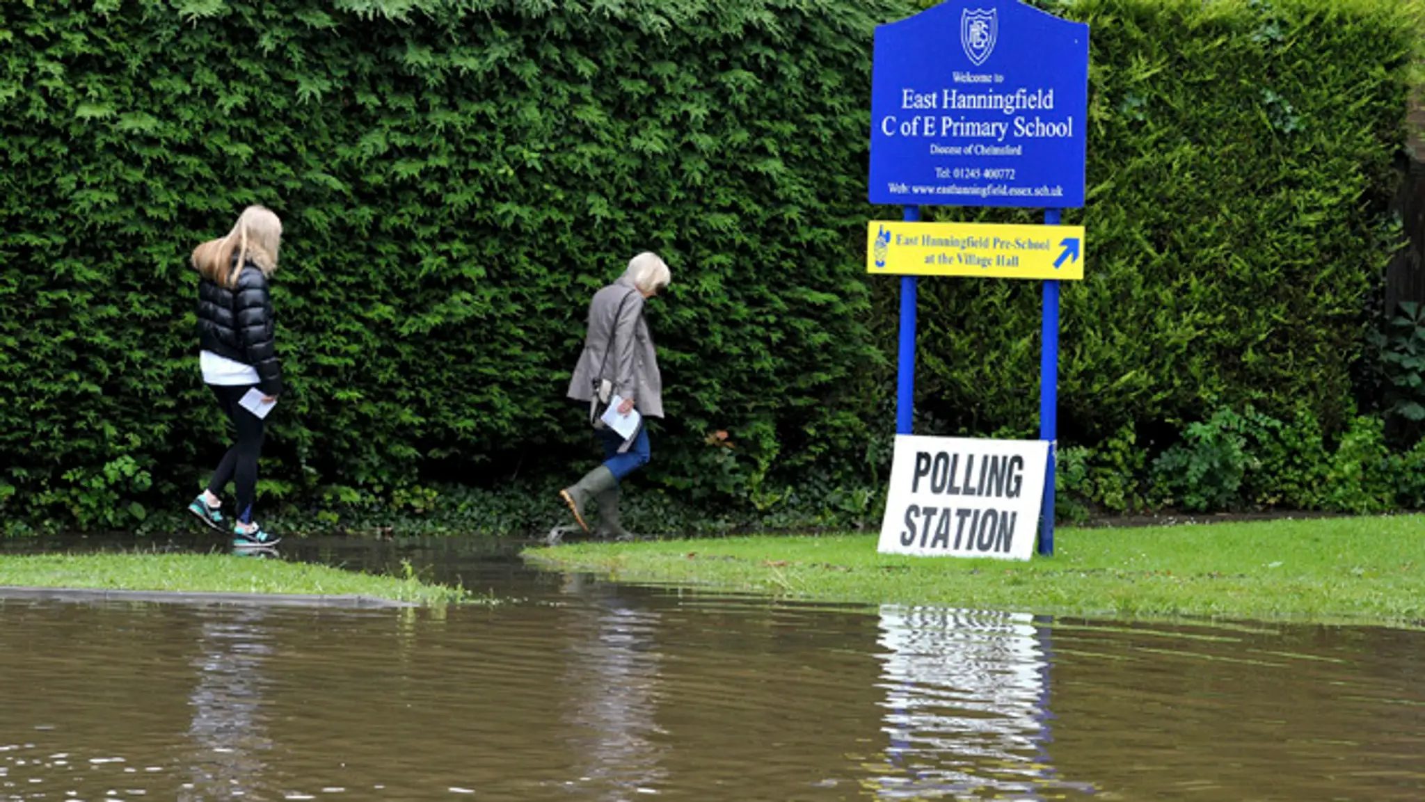 Ženy obchádzajú zaplavený chodník, keď idú odovzdať svoj hlas v rámci referenda o zotrvaní v Európskej únii.