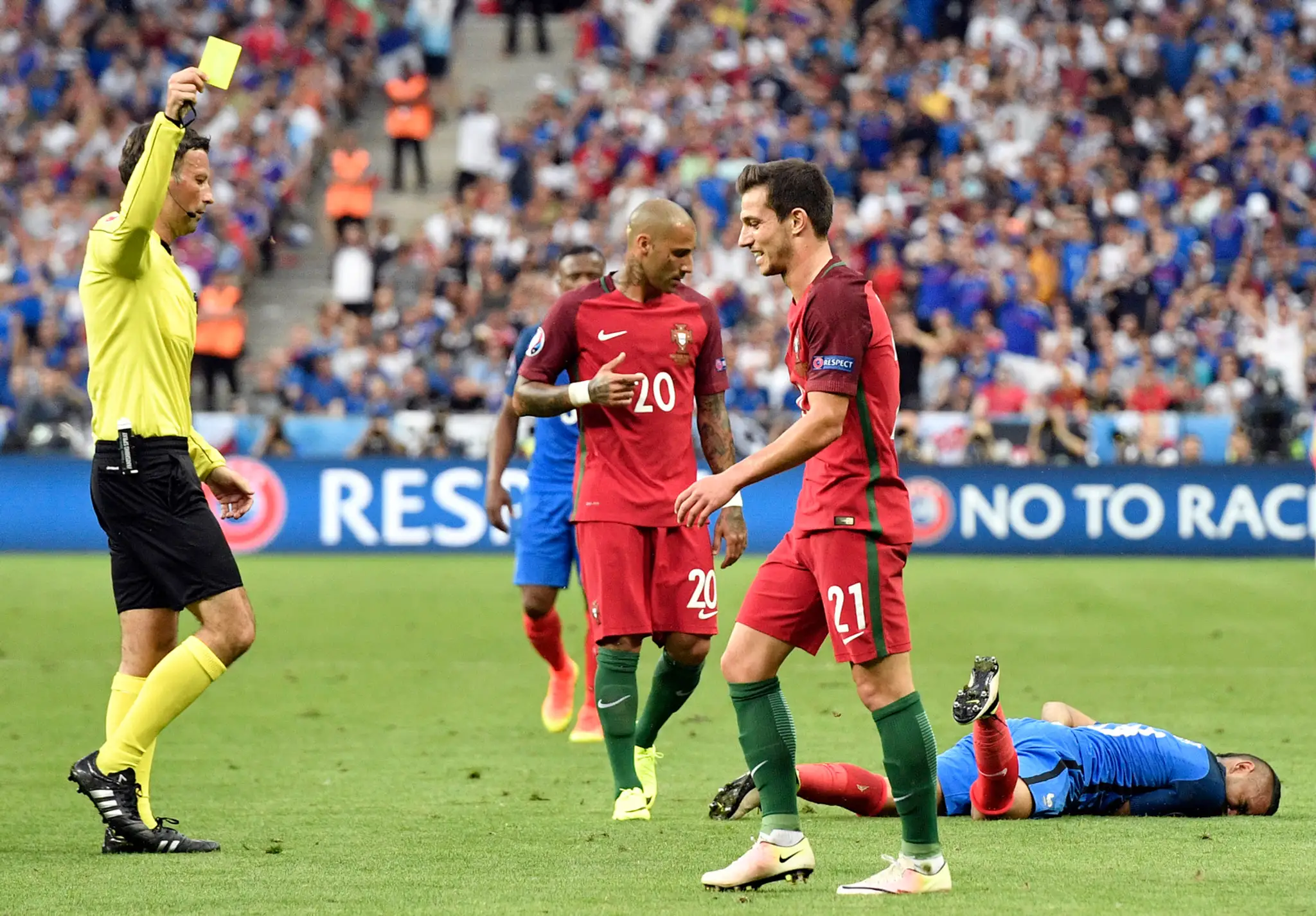 Arbiter Mark Clattenburg udeľuje žltú kartu Portugalčanovi Cedricovi (v popredí) po faule na Francúza Dimitriho Payeta vo finále