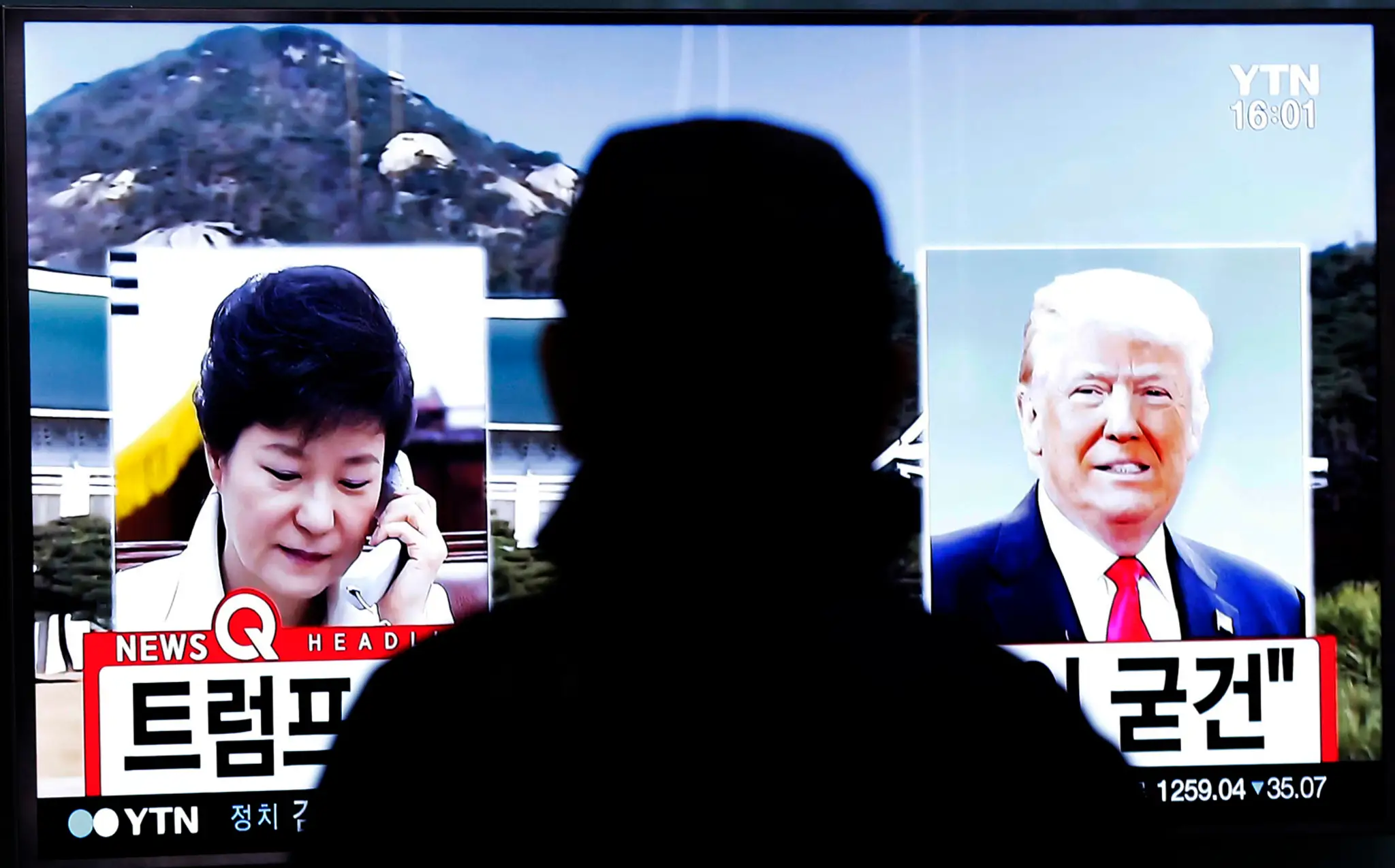 Muž sa pozerá na televíznu obrazovku, na ktorej sú podobizne budúceho amerického prezidenta Donalda Trumpa a juhokórejskej prezi