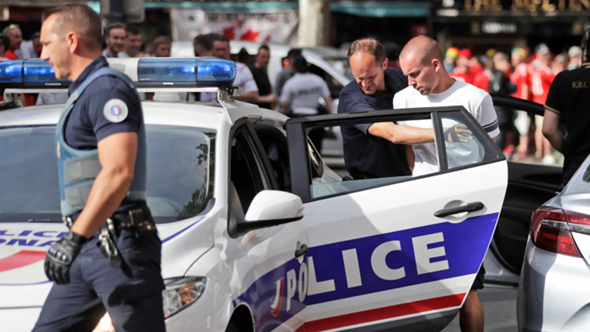 Policajt vedie zatknutého ruského fanúšika pred zápasom ME medzi Ruskom a Walesom.
