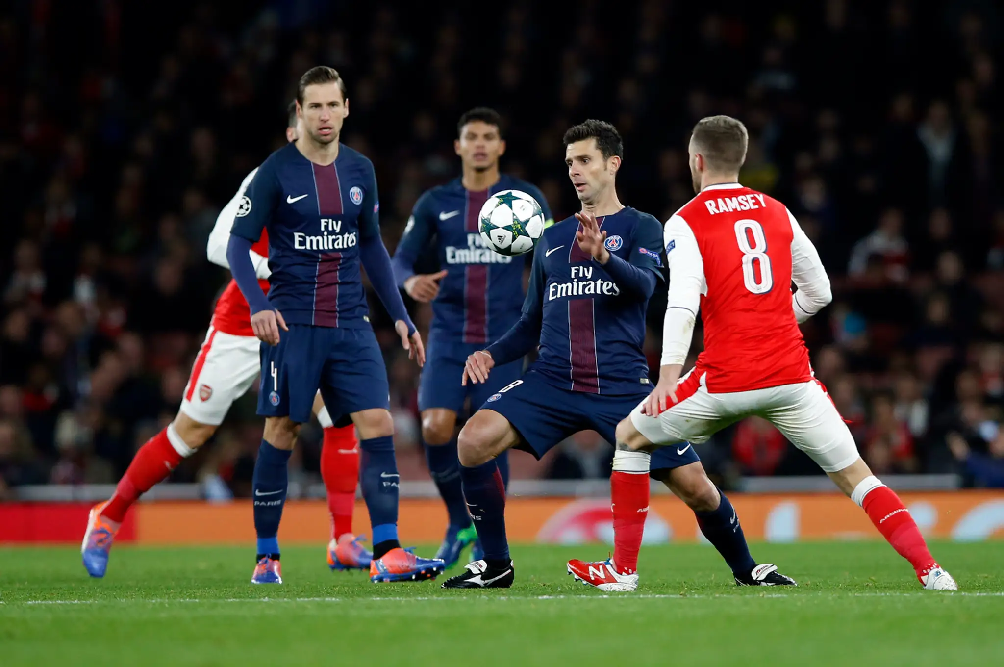 V súboji o loptu Aaron Ramsey (v červenom) z Arsenalu proti Thiagovi Mottovi z PSG v zápase LM.
