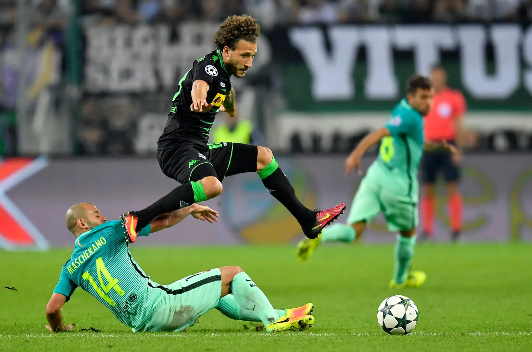 Vo výskoku hráč Borussie Mönchengladbach Fabian Johnson, na zemi v ostrom sklze defenzívna opora Barcelony Javier Mascherano v d