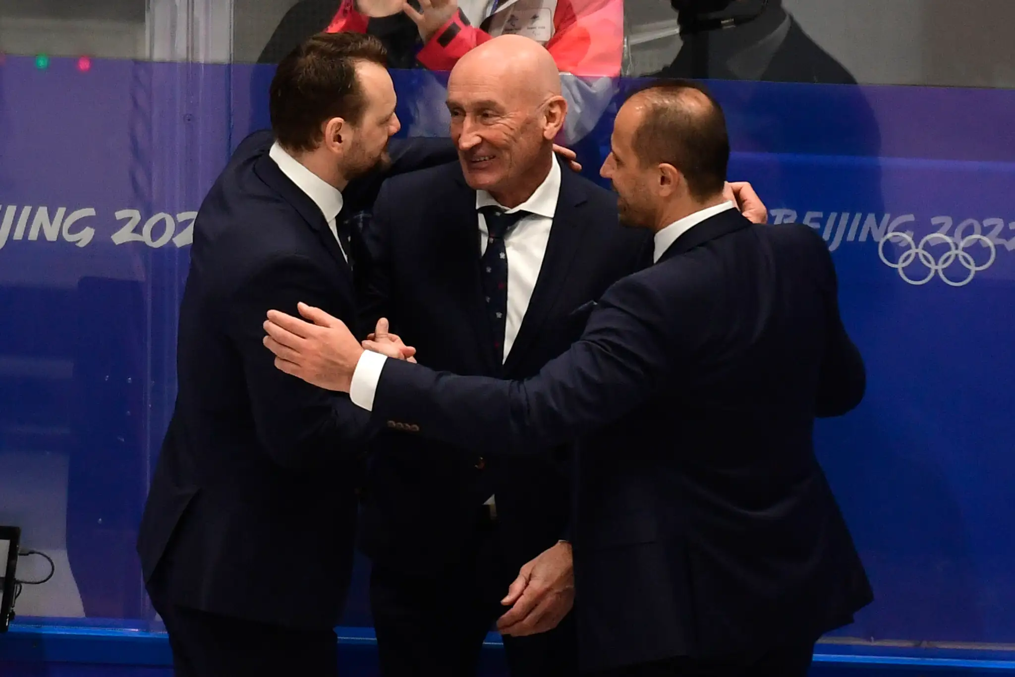 Zľava asistent trénera Andrej Podkonický, tréner Craig Ramsay a asistent trénera Ján Pardavý sa tešia po víťazstve v kvalifikácii o štvrťfinále nad Nemeckom na ZOH 2022.