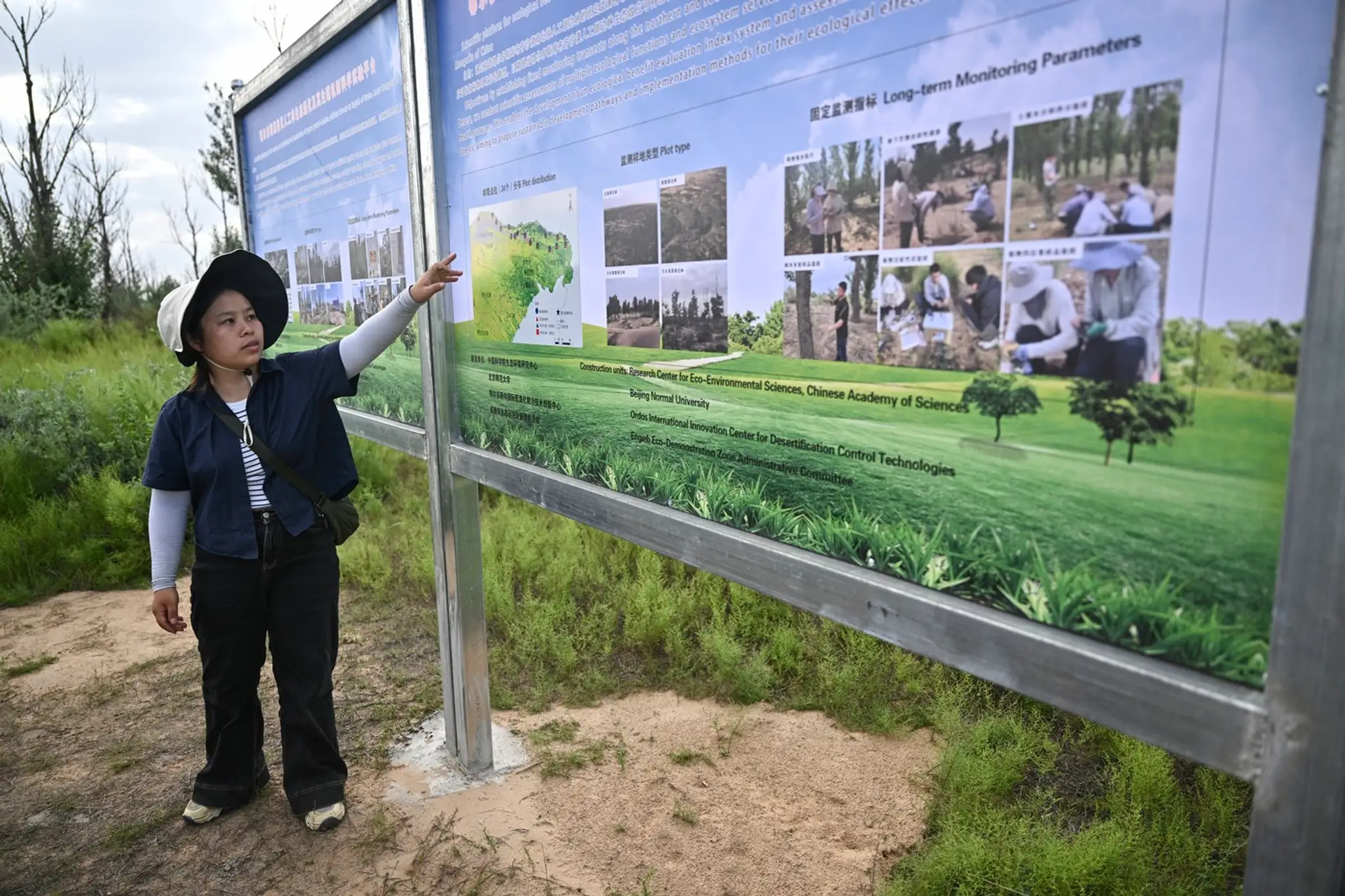 Na tejto fotografii z 11. augusta 2025 študentka Zhang Yanping vysvetľuje projekt zalesňovania suchých a púštnych oblastí, známy ako „Veľký zelený múr“.