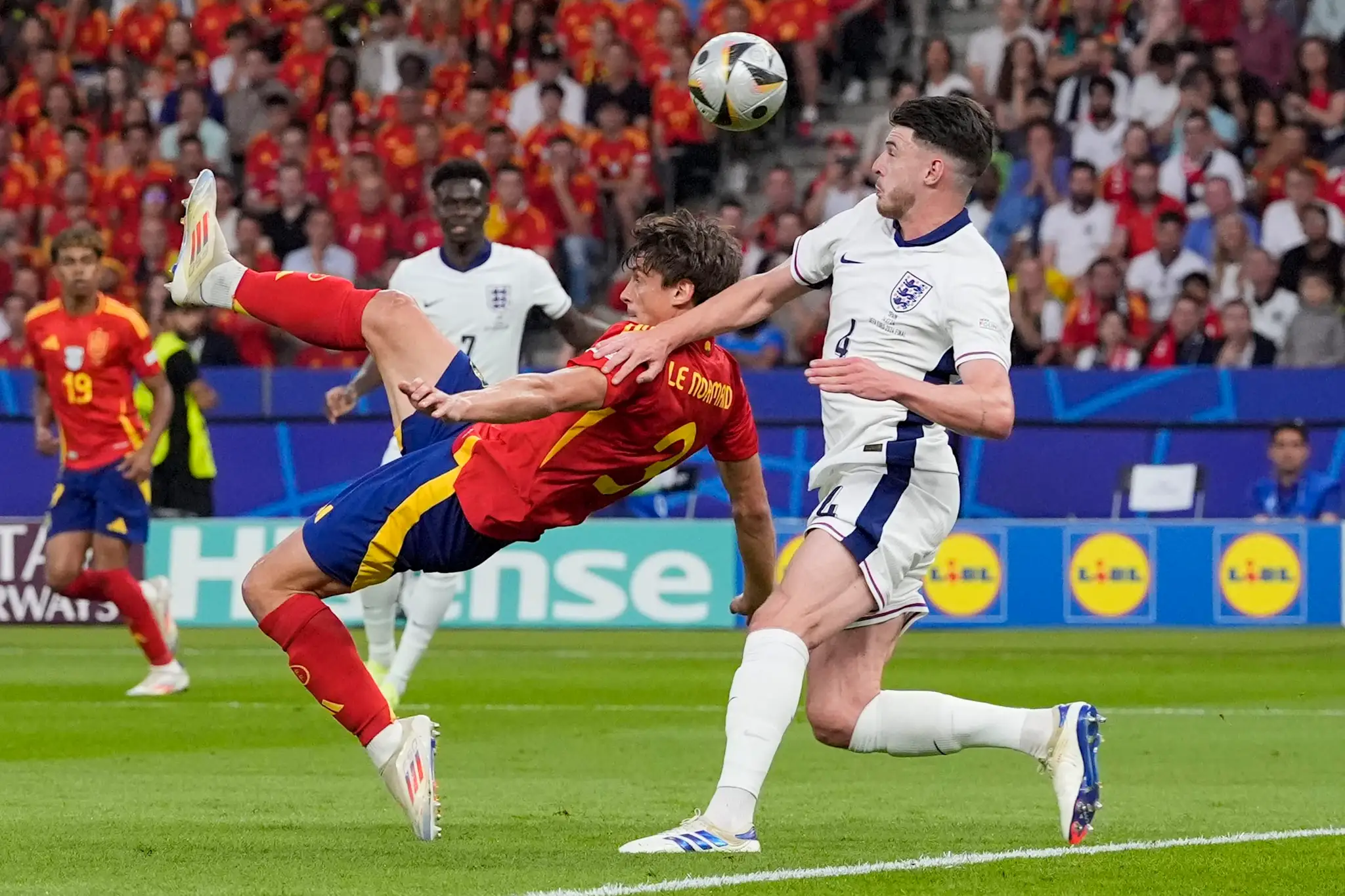 Vľavo Španiel Joselu strieľa vo finále ME 2024, snaží sa ho zblokovať Angličan Declan Rice.