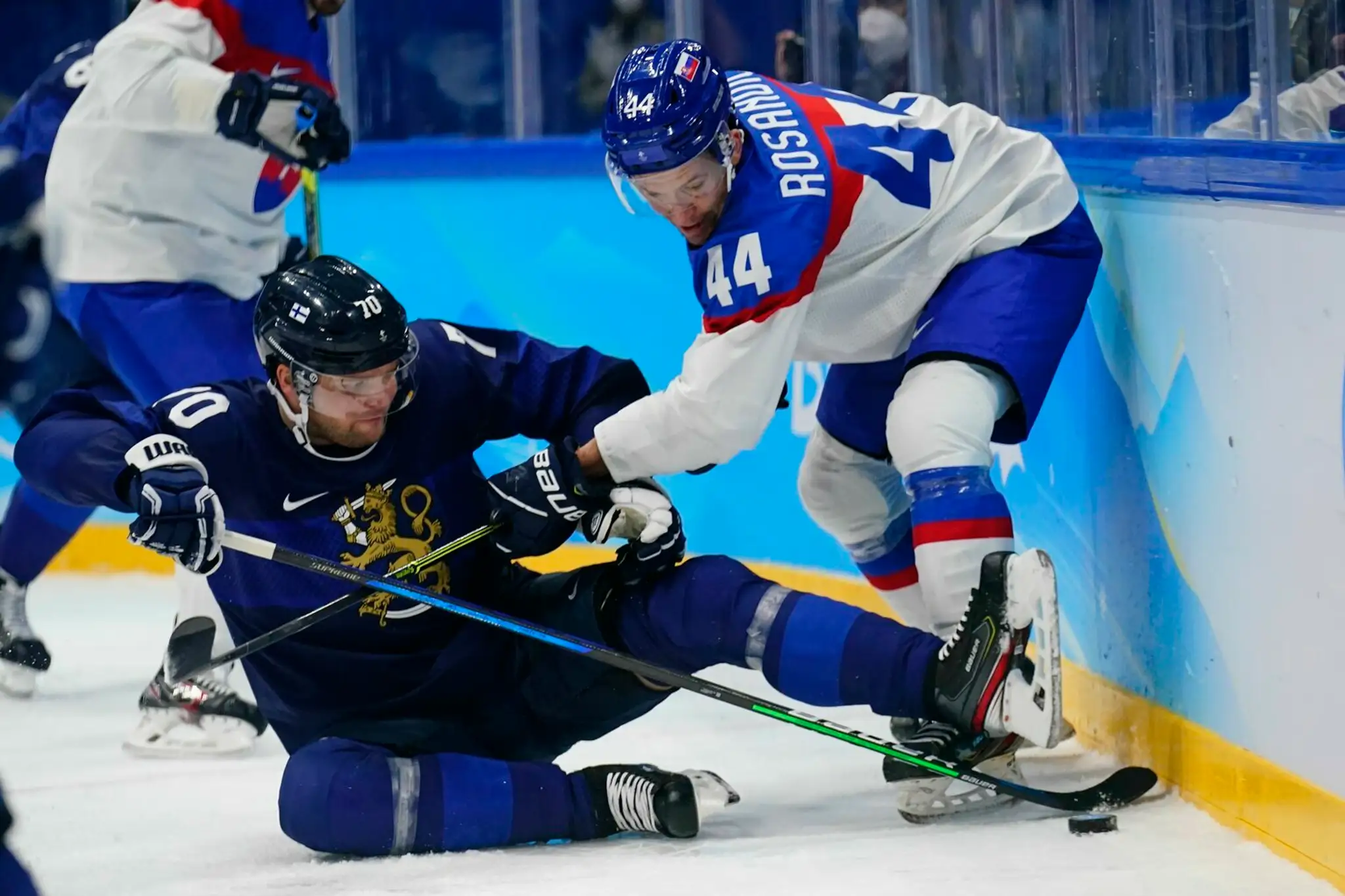 Zľava Fín Teemu Hartikainen a Mislav Rosandič bojujú o puk v dueli ZOH 2022.
