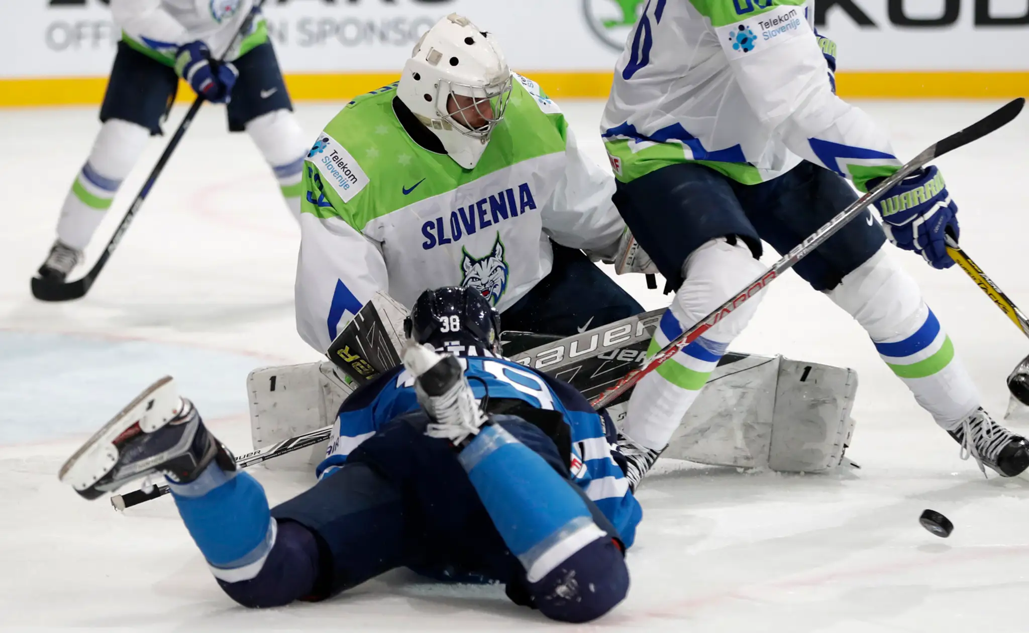 Slovinský brankár Gasper Kroselj (v pozadí) chytá puk pred Juusom Hietanenom z Fínska v dueli MS 2017.
