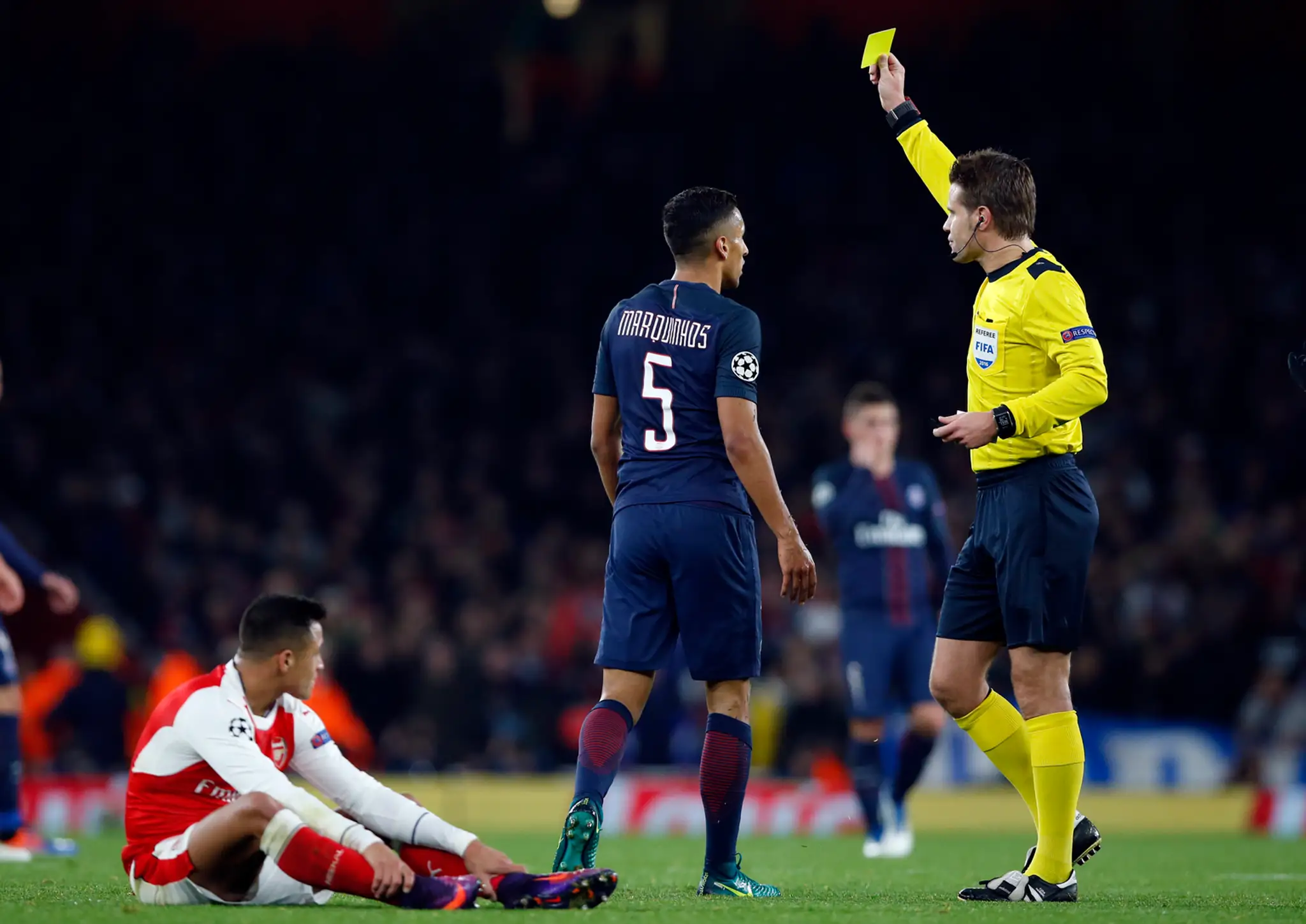 Arbiter Felix Brych ukazuje žltú kartu bekovi PSG Marquinhosovi v dueli LM proti Arsenalu.