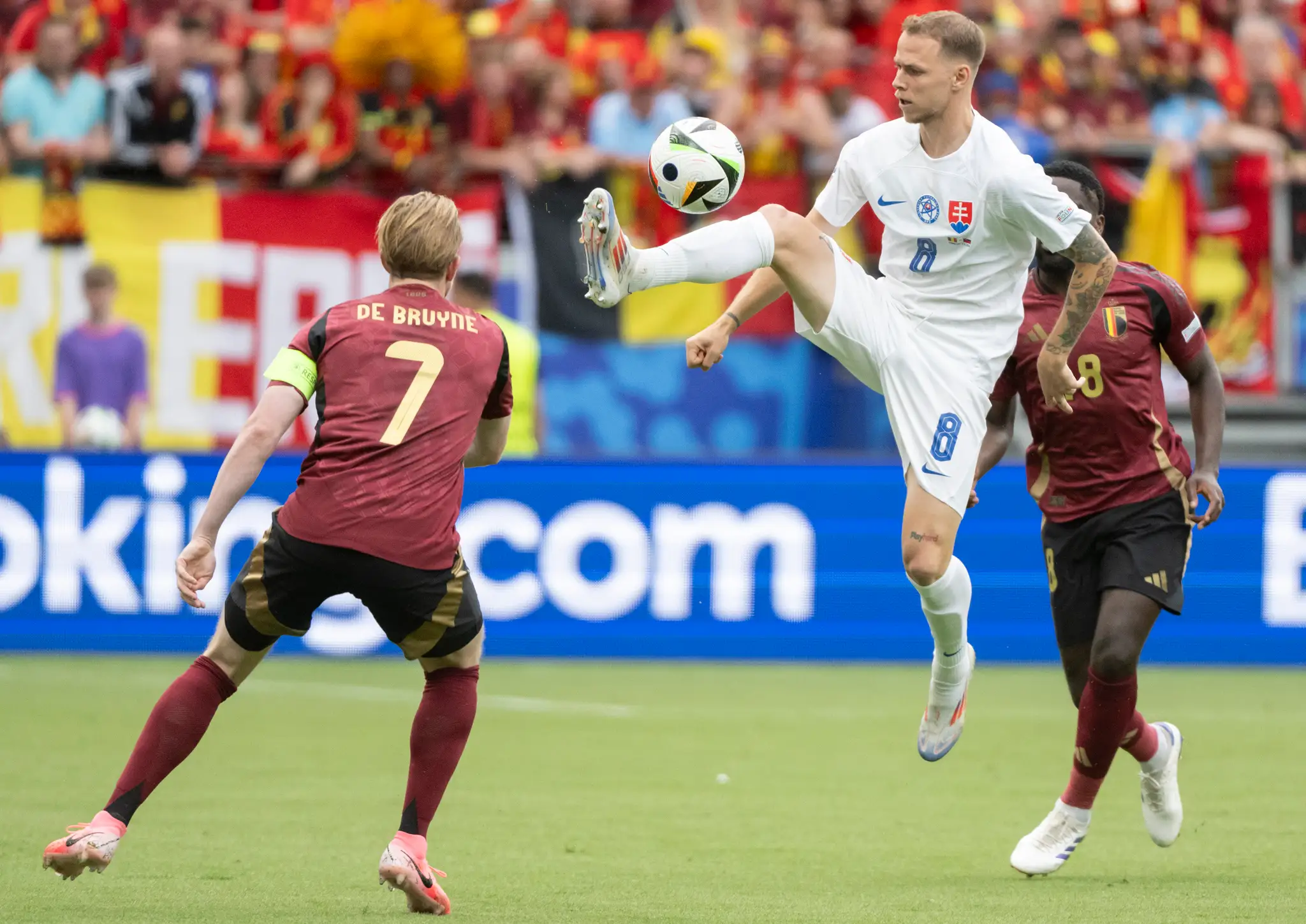 Slovenský futbalista Ondrej Duda (uprostred) a kapitán Belgicka Kevin De Bruyne (vľavo) bojujú o loptu