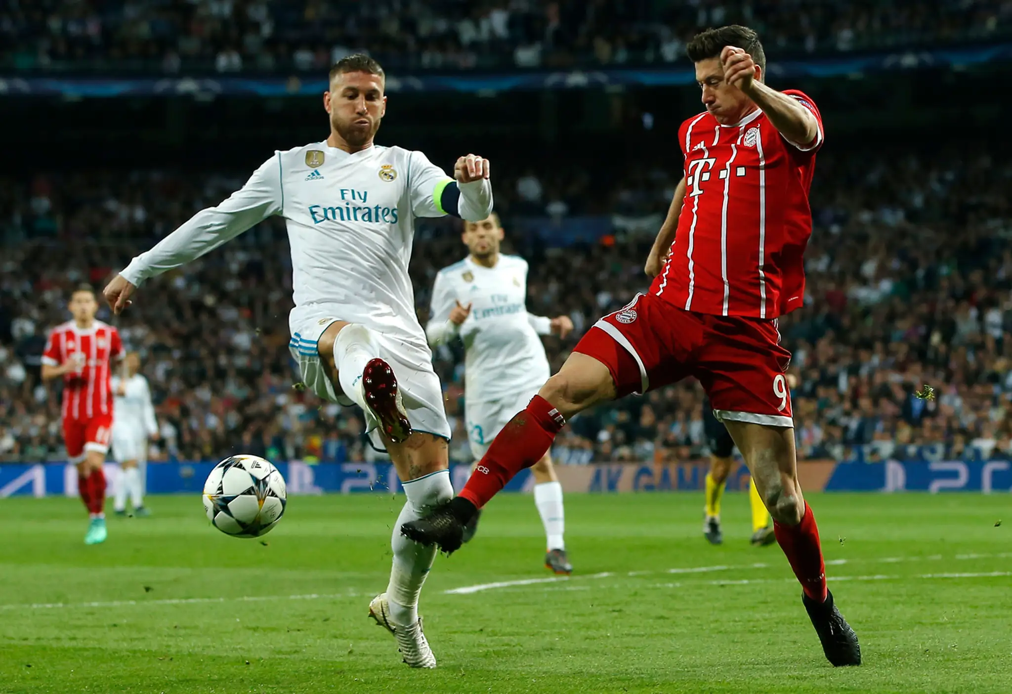 Robert Lewandowski (vpravo) z Bayernu bojuje o loptu s kapitánom Realu Sergiom Ramosom v odvete semifinále LM.