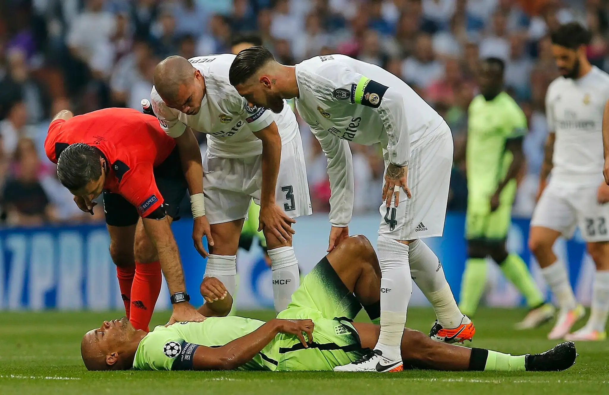 Arbiter Damir Skomina (v červenom), hráči Realu Pepe a Sergio Ramos (s kapitánskou páskou) hľadia na zraneného Vincenta Kompanyh