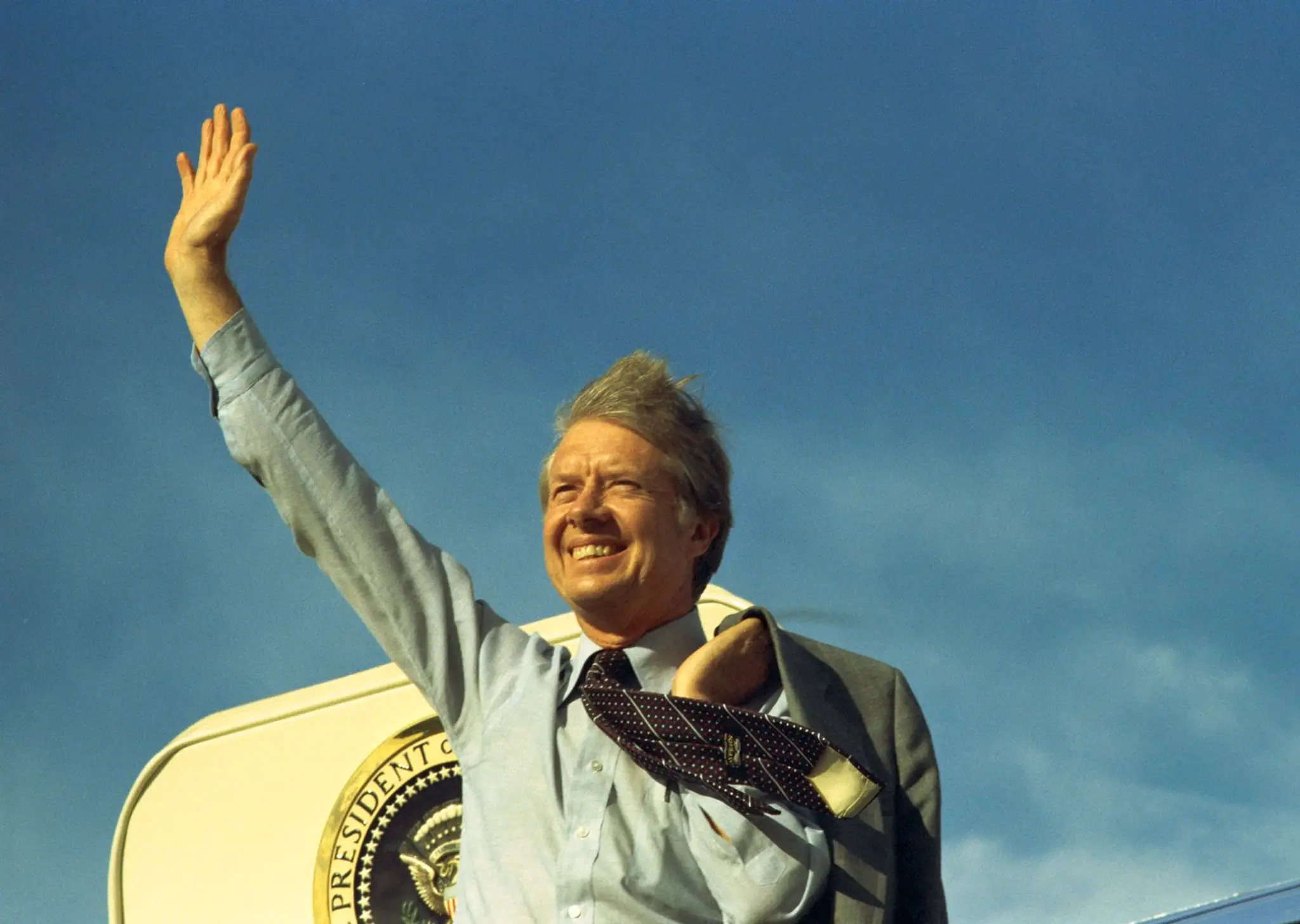 Americký prezident Jimmy Carter mával na schodoch Air Force One pred odletom do Los Angeles, aby vystúpil na zjazde United Auto Workers 17. mája 1977.