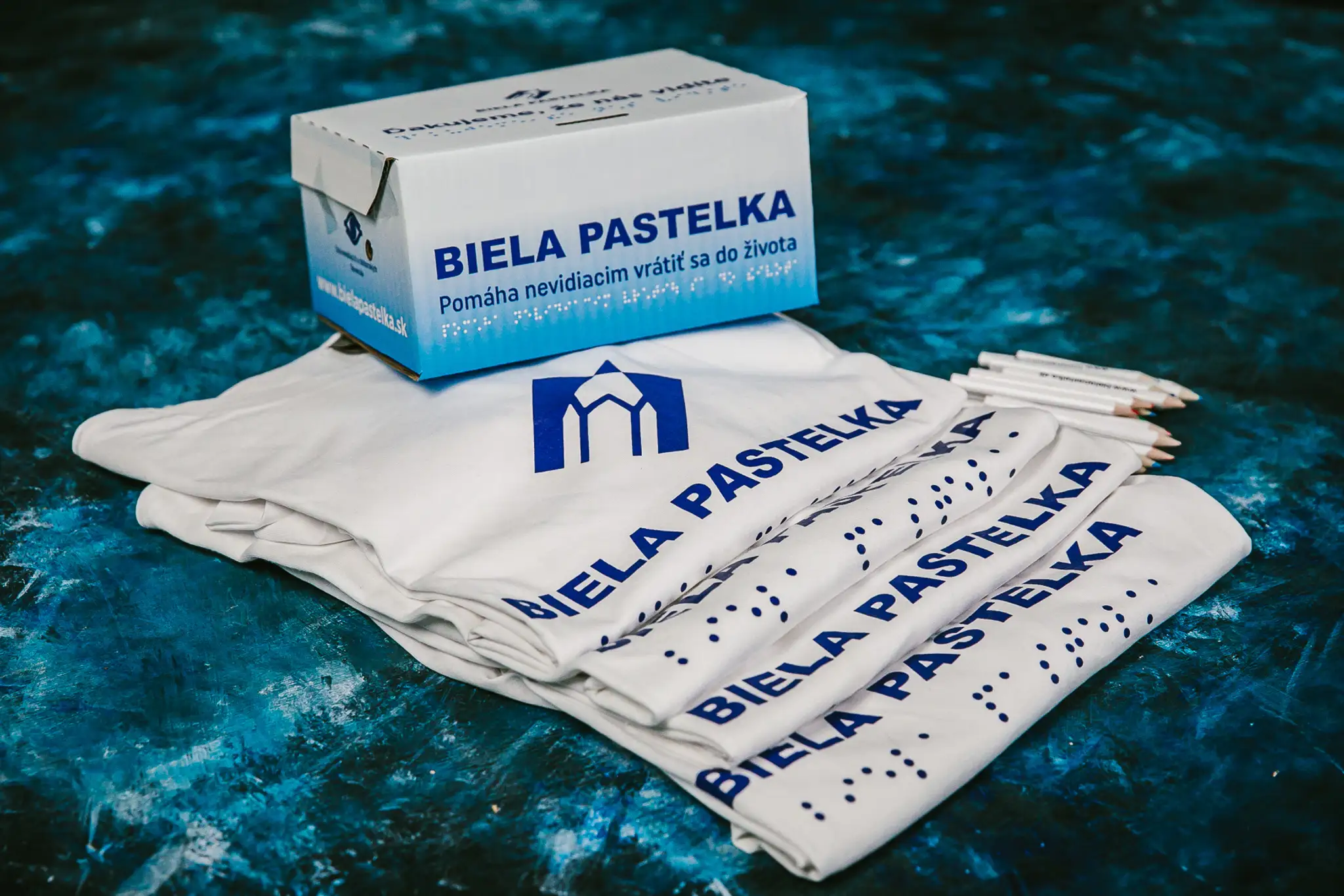 Tričká pre dobrovoľníkov, pokladničky a pastelky zbierky Biela pastelka. Dobrovoľníkov stretnete v uliciach 23. septembra.