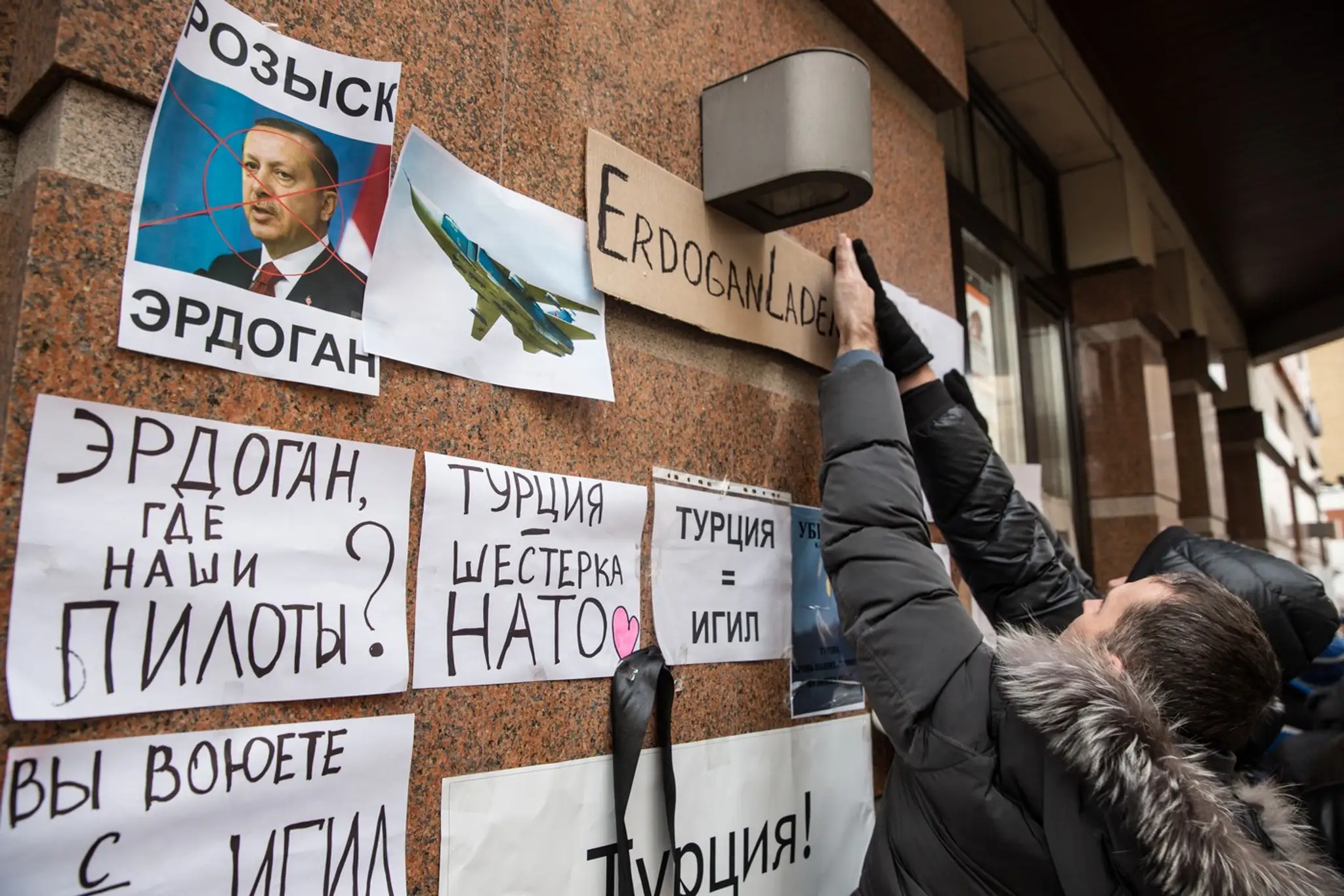 TASS Rusi počas demonštrácie pred tureckýmm veľvyslanectvom v Moskve lepia transparenty s nápismi ako „Erdogan je vrah“, „Erdogan, kde sú naši piloti“ alebo „Turecko je ISIS“.