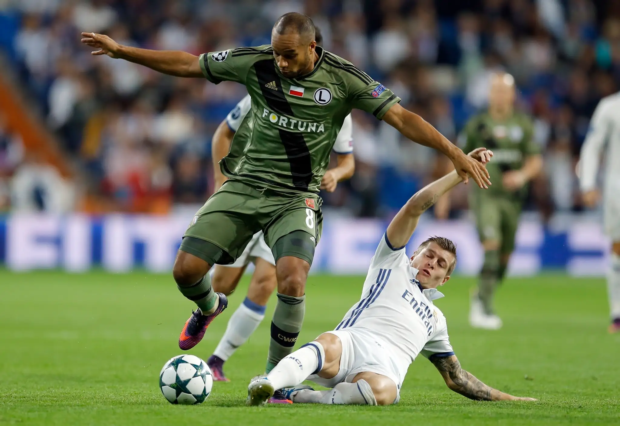 Hráč Legie Varšava Vadis Odjidja (vľavo) proti Toni Kroosovi z Realu Madrid v dueli LM.