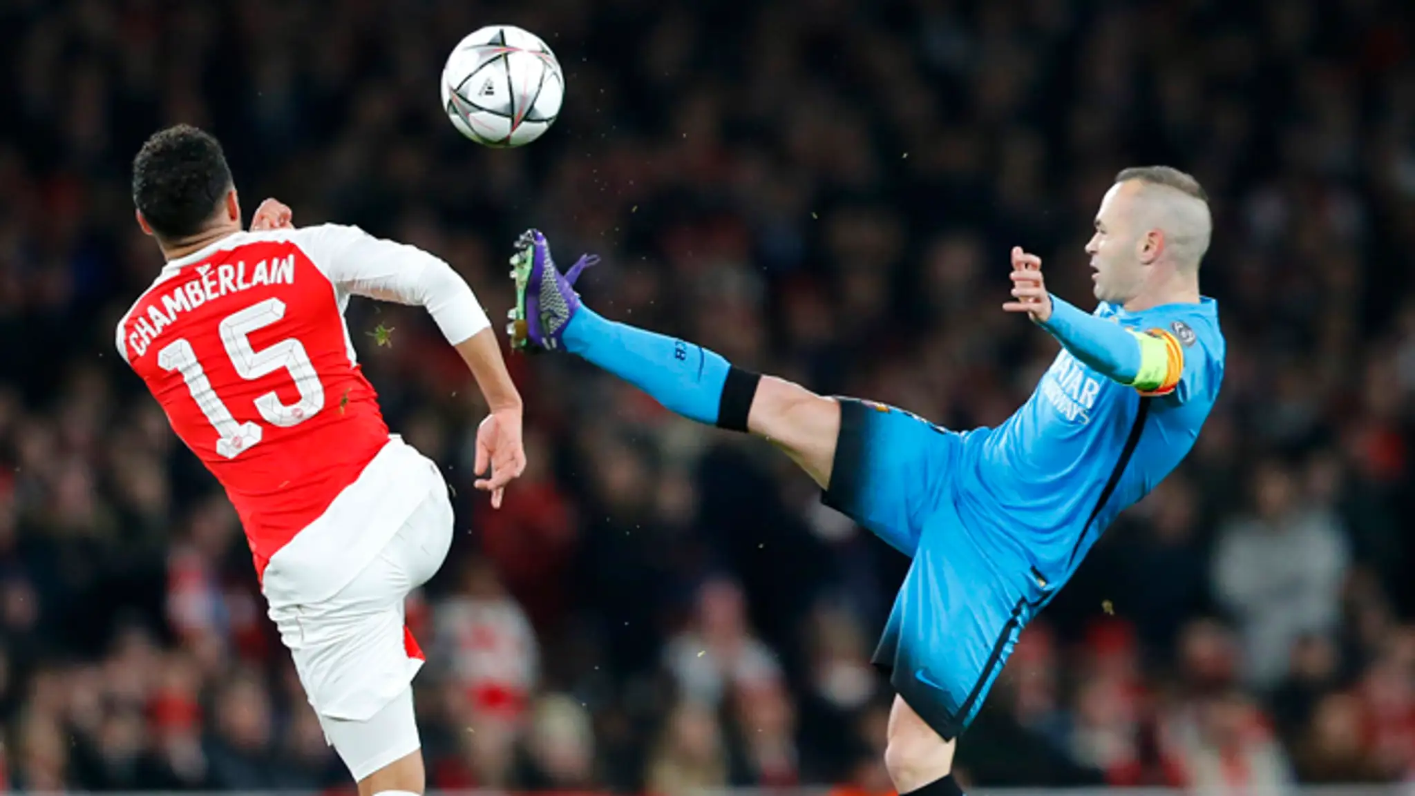 Vľavo hráč Alex Oxlade-Chamberlain (Arsenal) v súboji o loptu s André Iniestom (Barcelona).