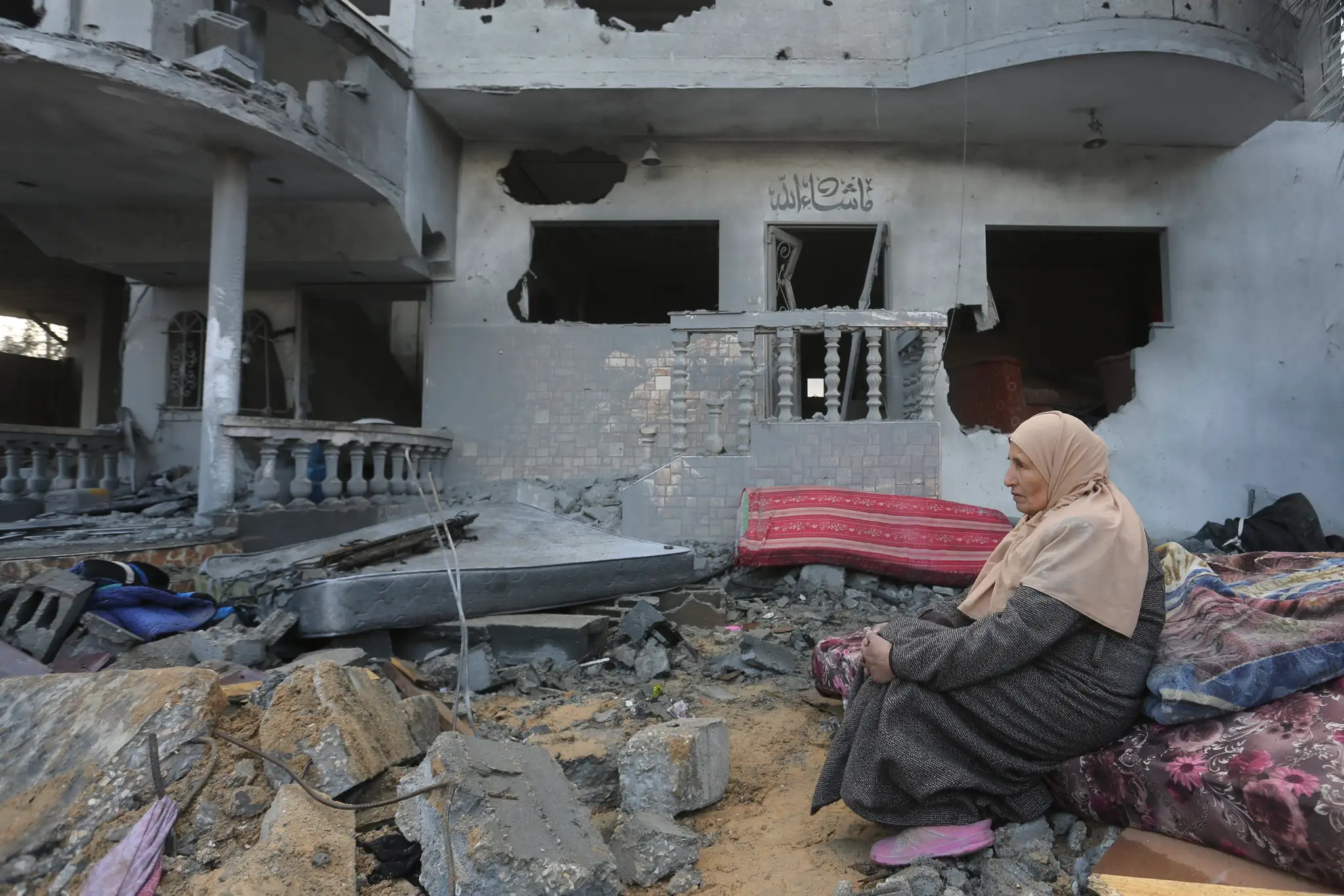 Palestínska žena sedí pri domoch zničených pri izraelskom bombardovaní v pásme Gazy.