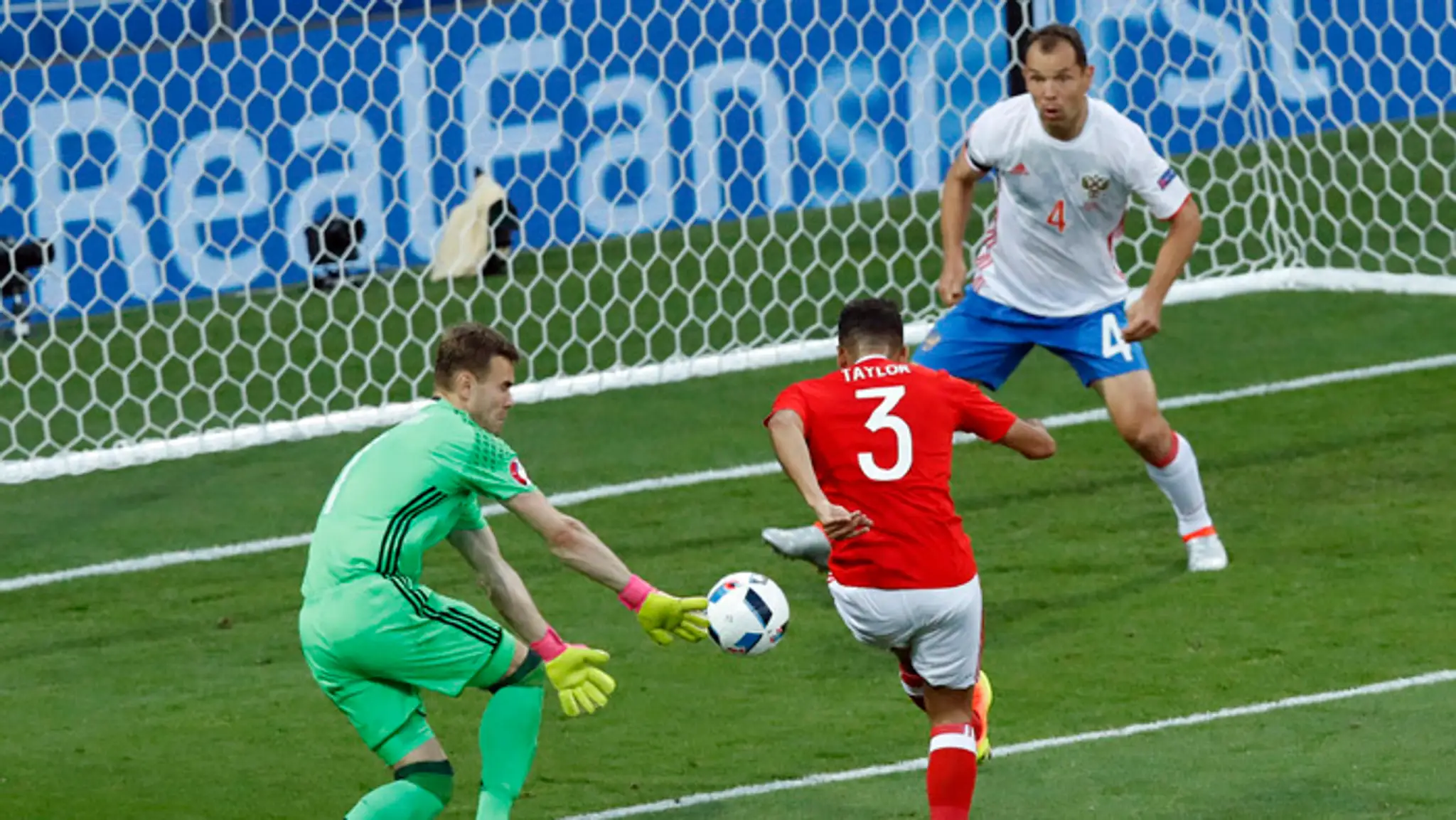 Walesan Neil Taylor (v strede) strieľa gól Igorovi Akinfejevovi (vľavo), vpravo Sergej Ignaševič.