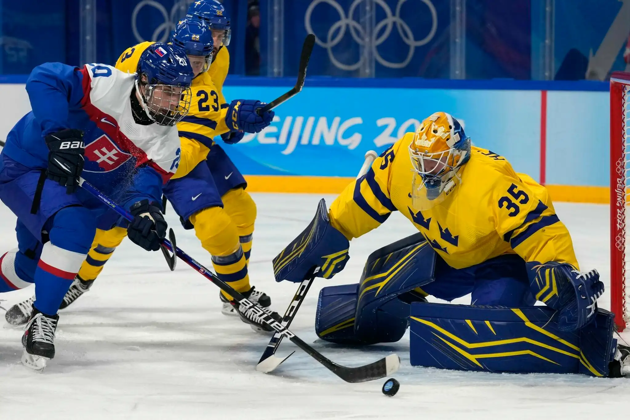 Zľava Juraj Slafkovský sa snaží v dueli na ZOH 2022 prekonať gólmana Švédska Magnusa Hellberga.