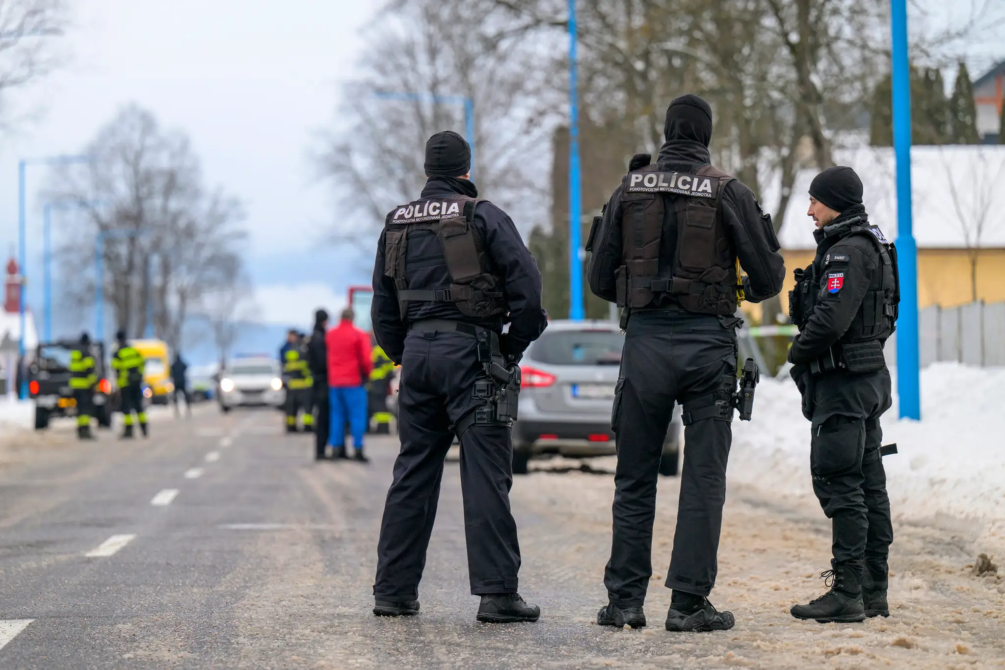 Policajti hliadkujú na ceste, ktorá vedie k budove gymnázia