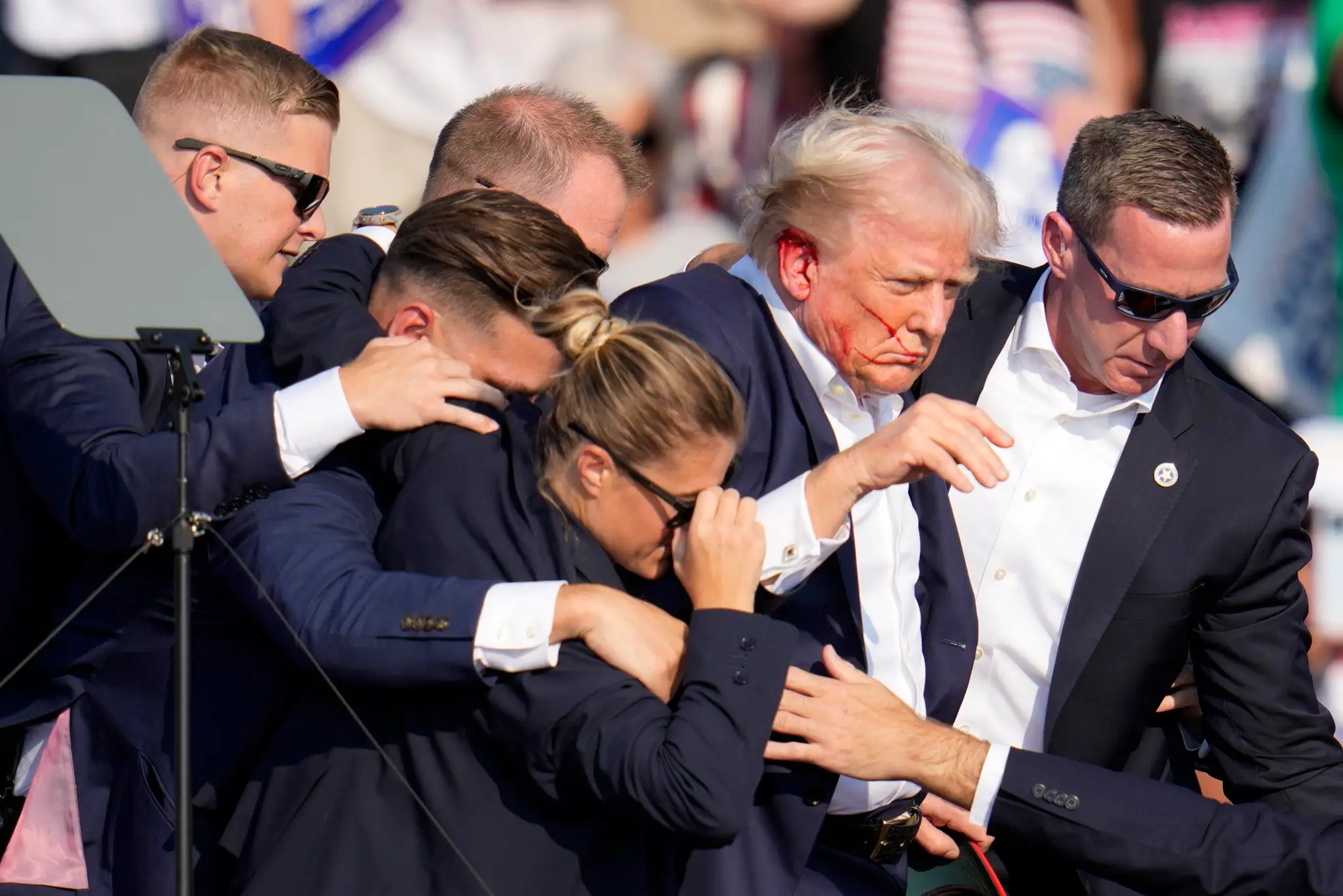 Postrelený Donald Trump odchádza z pódia.