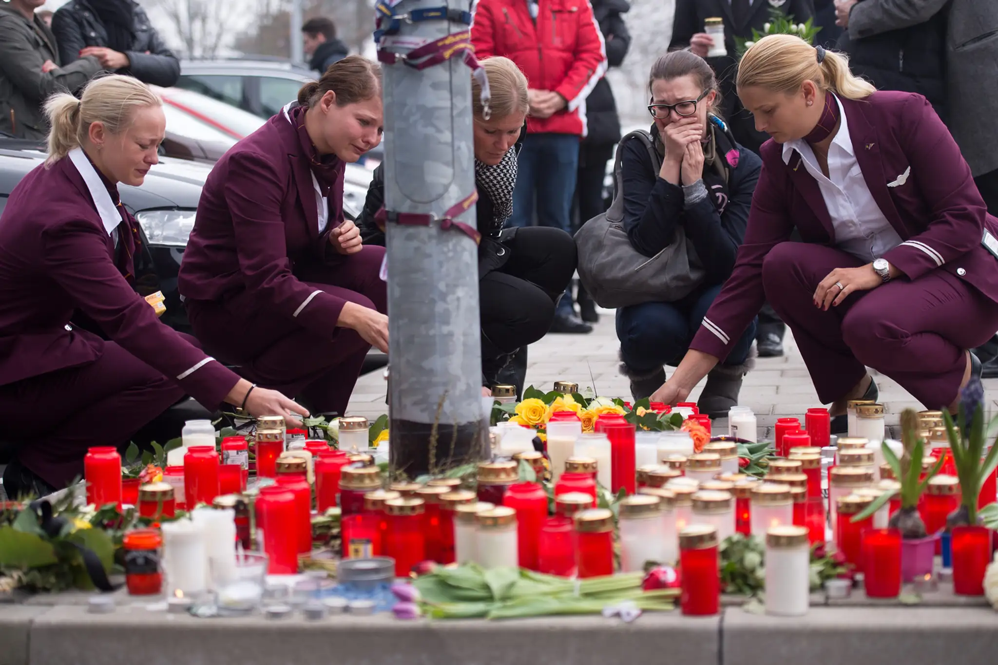 Zamestnankyne nemeckej spoločnosti Germanwings kladú sviečky a kvety pred sídlom leteckej spoločnosti Germanwings.