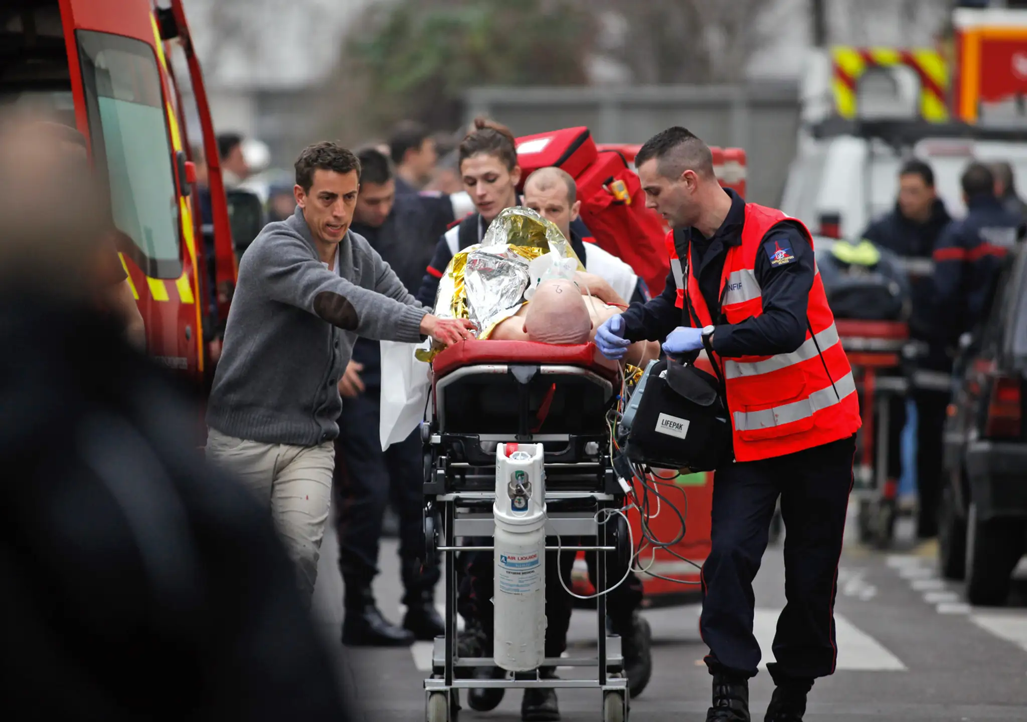 Zdravotníci prenášajú zranenú osobu z redakcie francúzskeho satirického týždenníka Charlie Hebdo