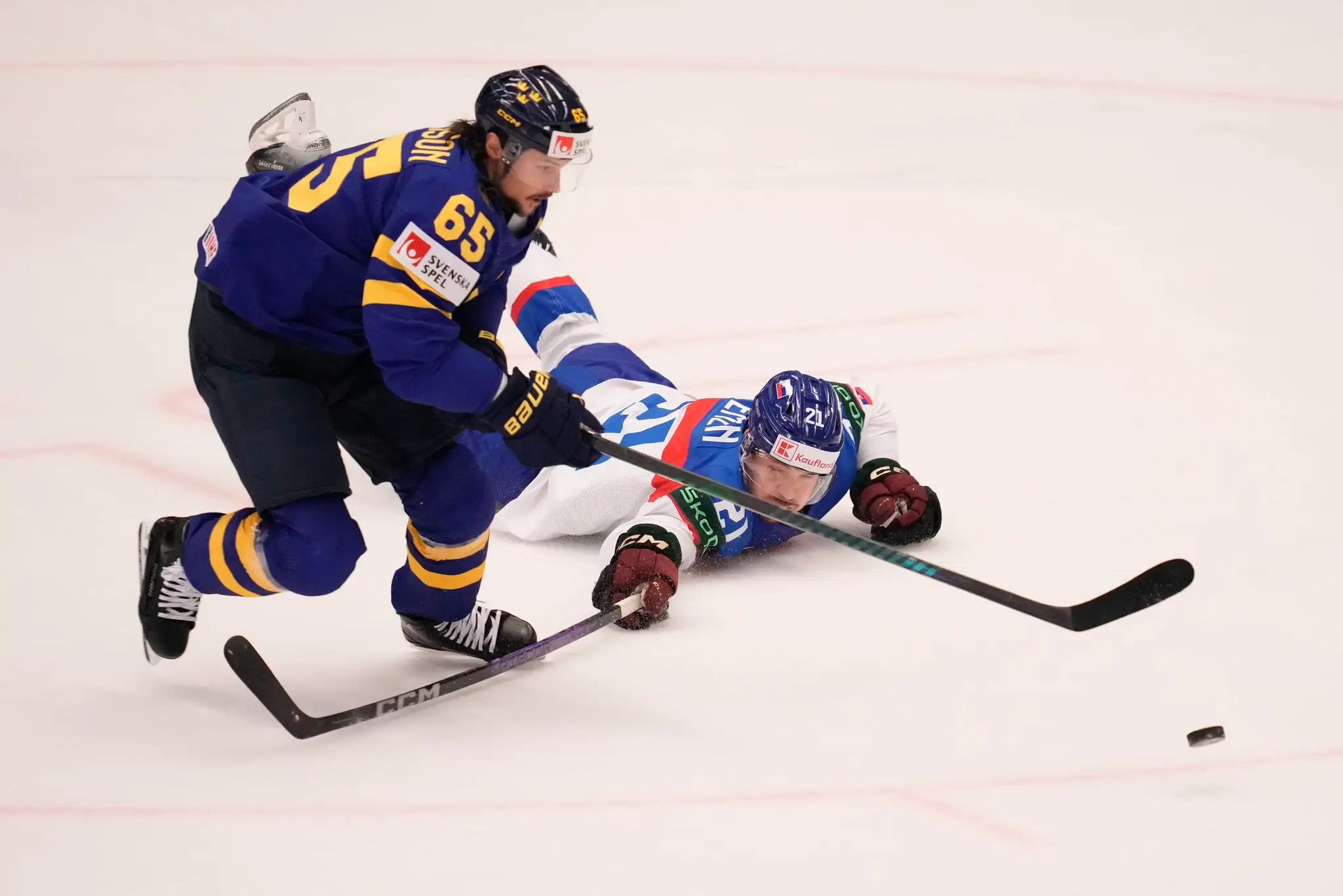 Zľava Švéd Erik Karlsson a Miloš Kelemen bojujú o puk v zápase na MS 2024.