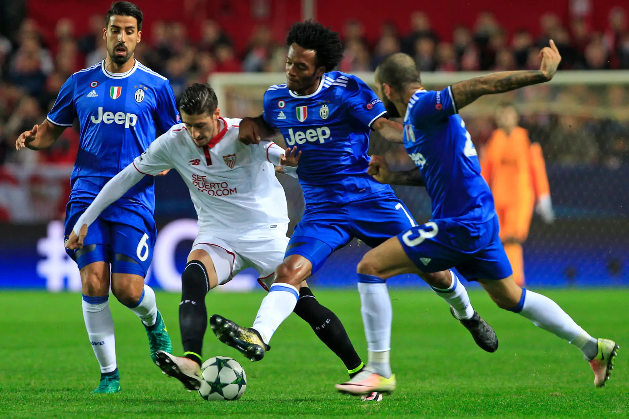 Dvojica z Juventusu Juan Cuadrado (vpravo vzadu) a Dani Alves sa snaží zastaviť Vicente Iborru z FC Sevilla v dueli LM.