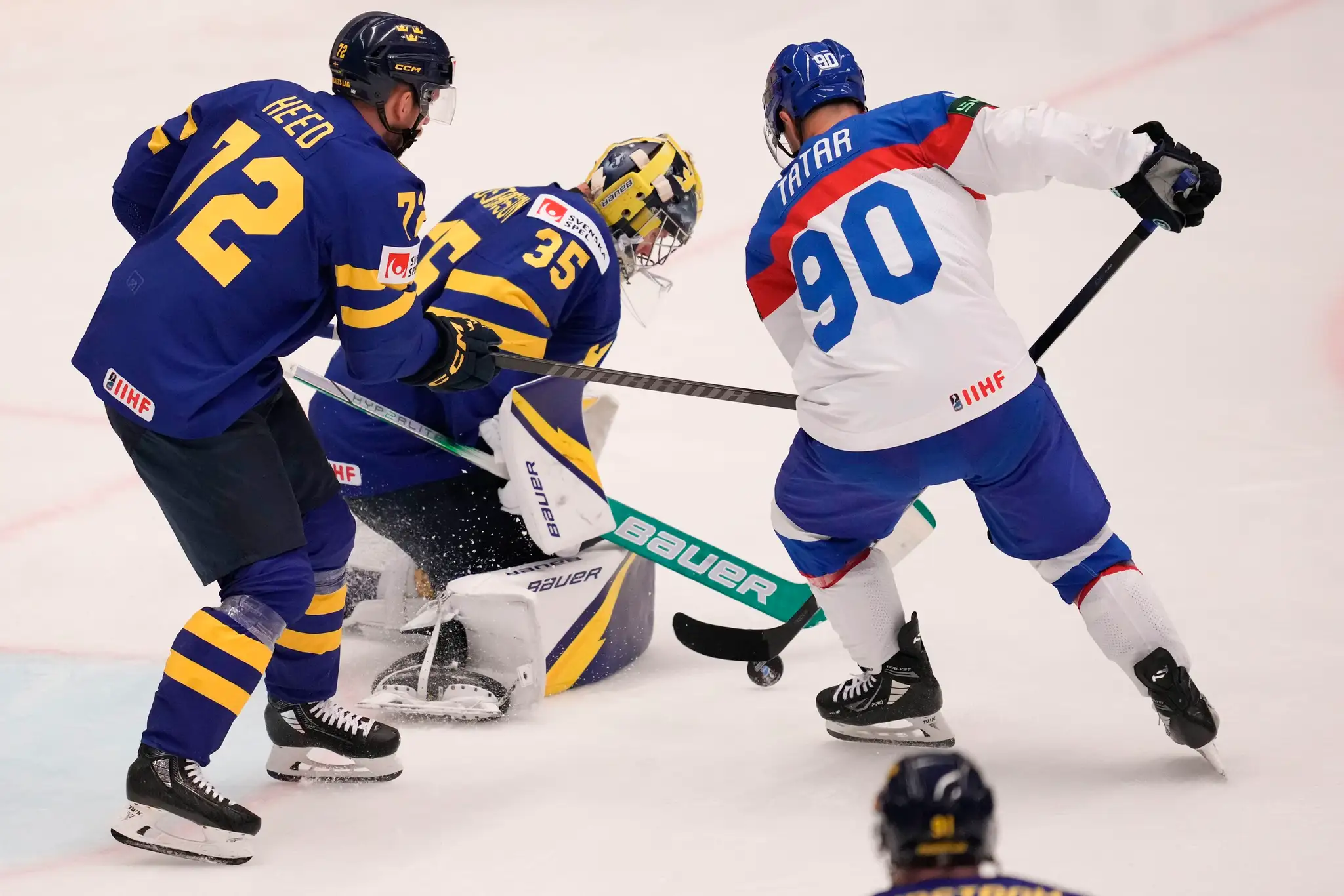 Švédsky brankár Filip Gustavsson ratuje puk pred Tomášom Tatarom v zápase MS 2024 proti Slovensku.