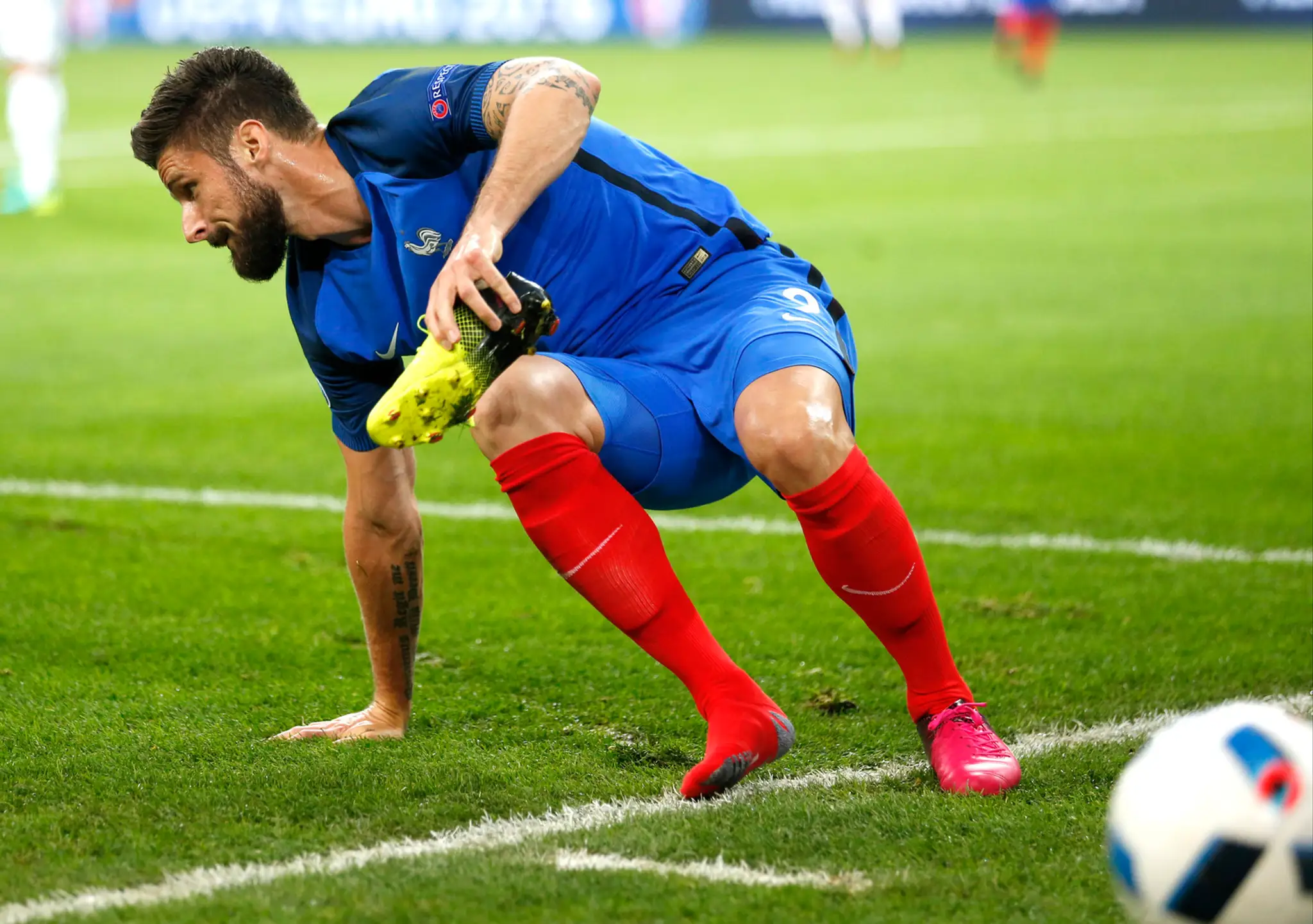 Snajper v tíme Francúzska Olivier Giroud si obúva kopačku v dueli proti Francúzsku na ME.