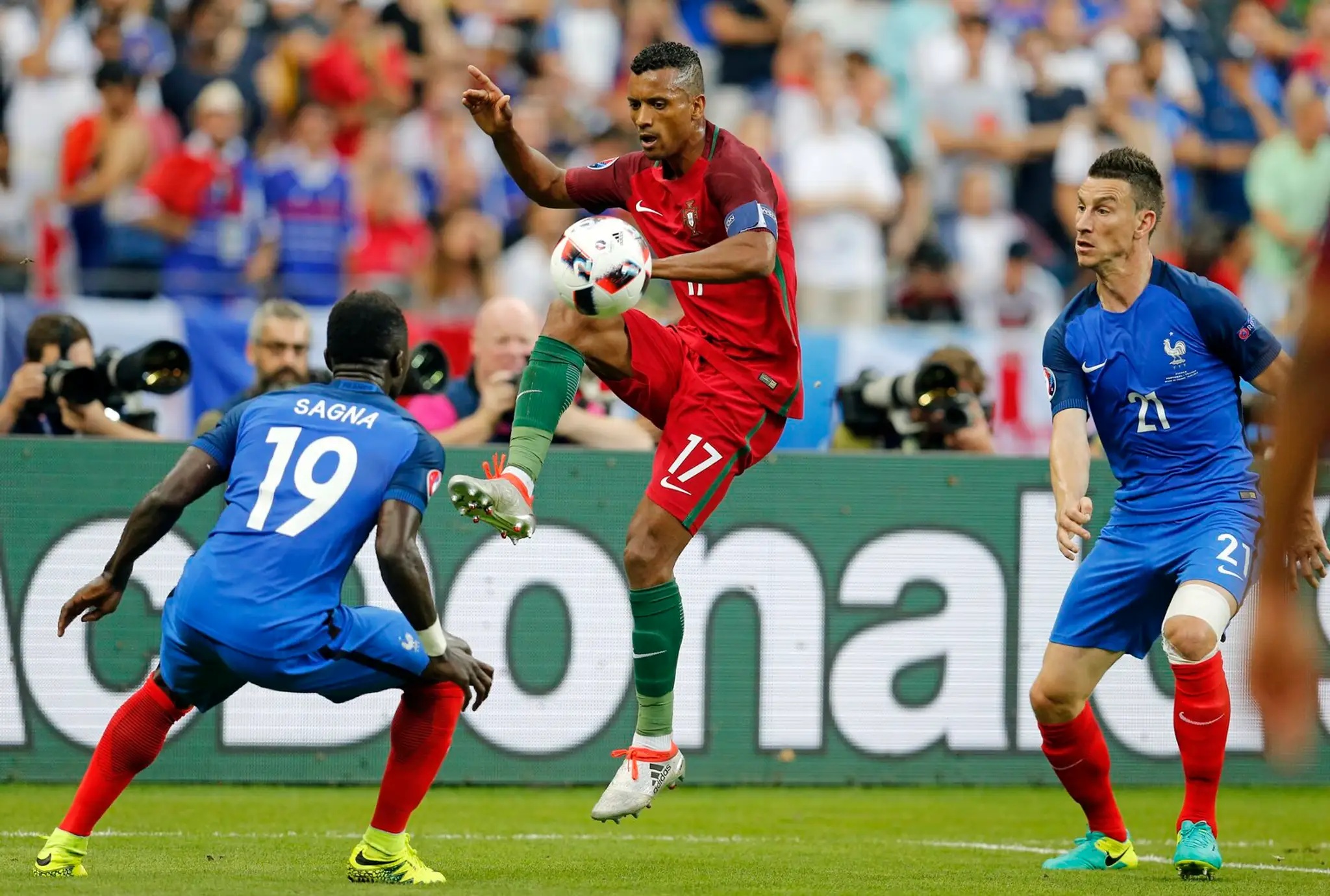 Portugalčan Nani s loptou proti Francúzom Bacarymu Sagnovi a Laurentovi Koscielnemu vo finále ME.