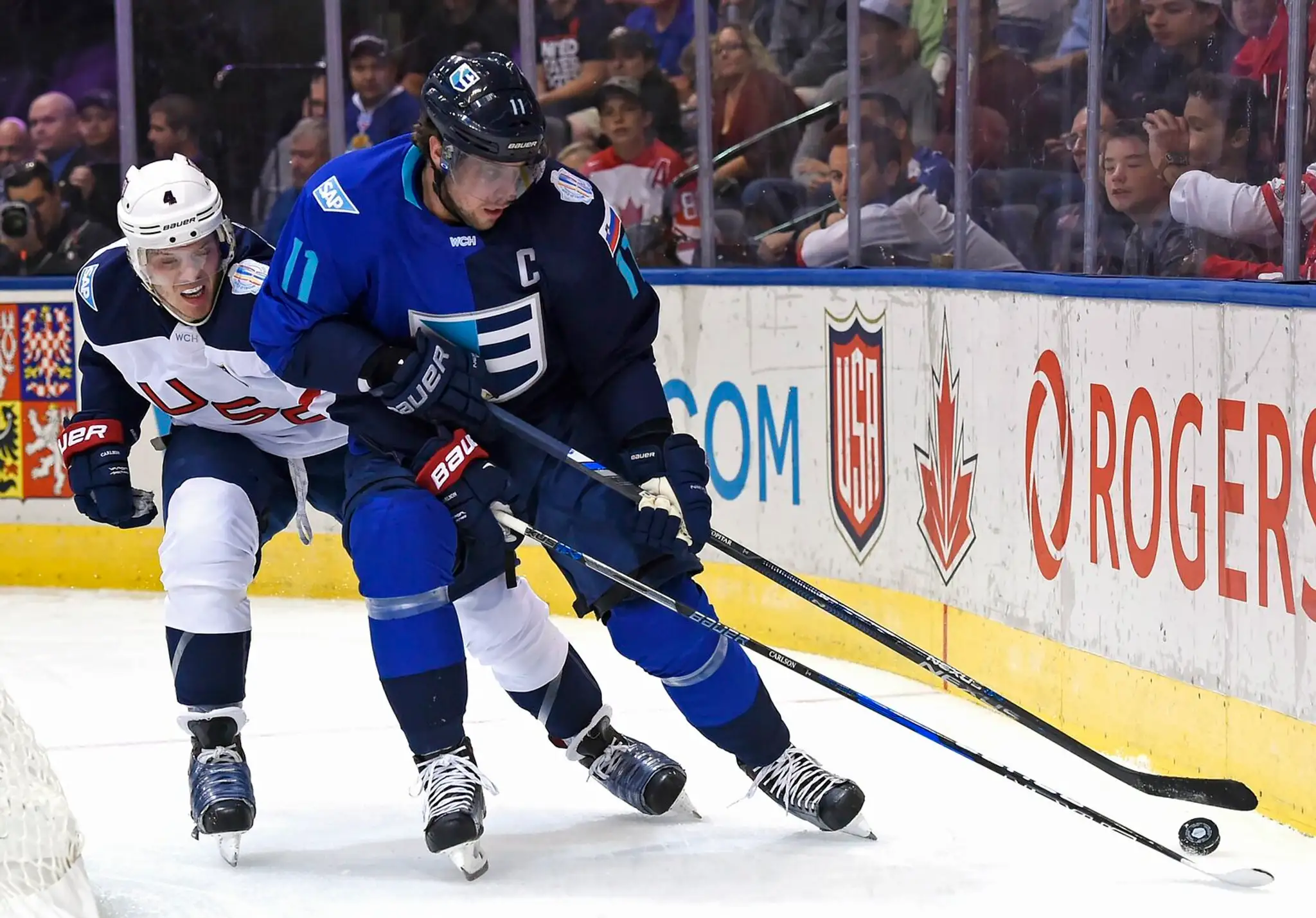 Kapitár Tímu Európy Slovinec Anže Kopitar si kryje puk pred Američanom Johnom Carlsonom.