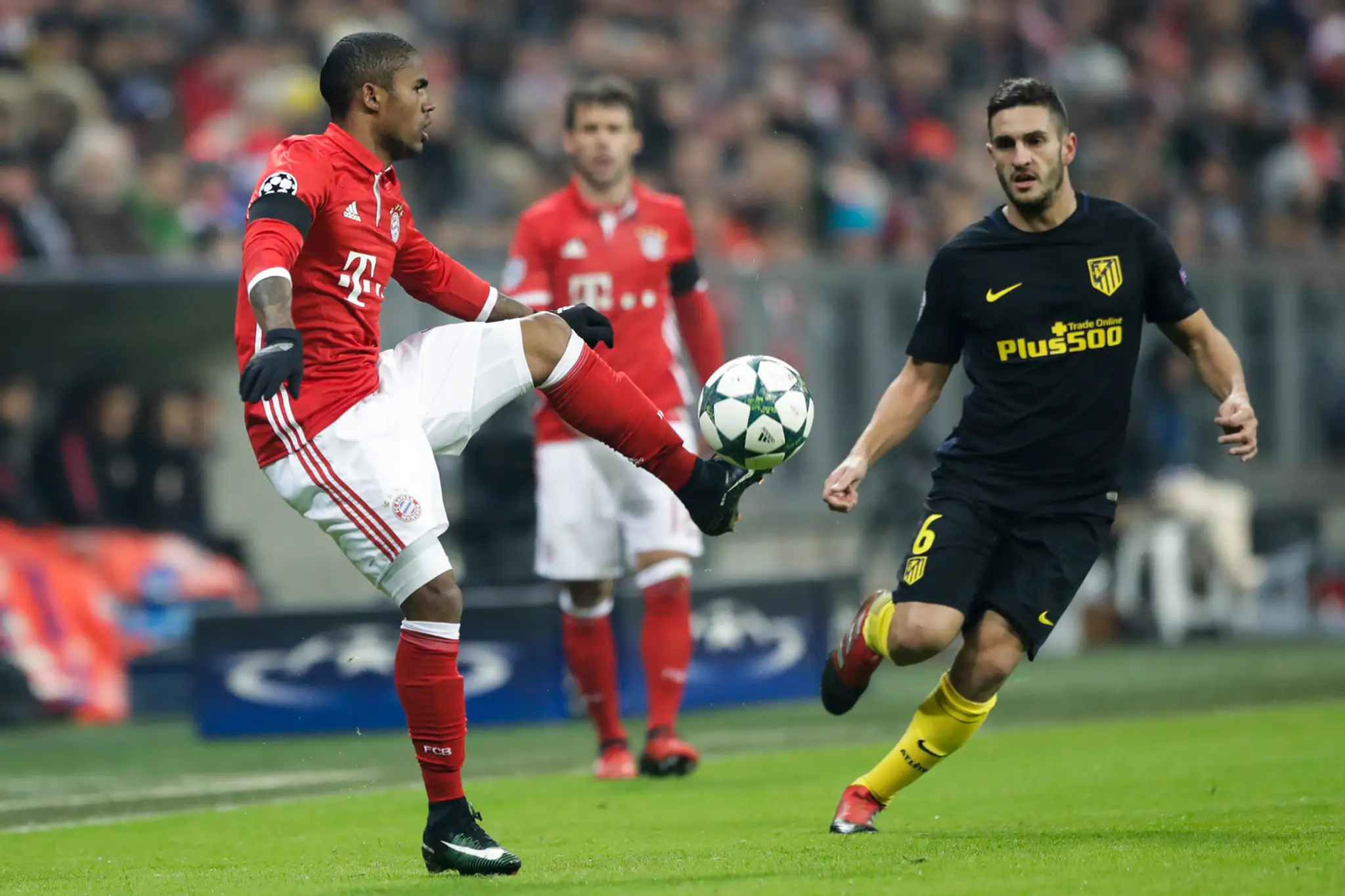 Douglas Costa (vľavo) z Bayernu Mníchov si zakrýva loptu v zápase LM proti Kokemu z madridského Atlética.