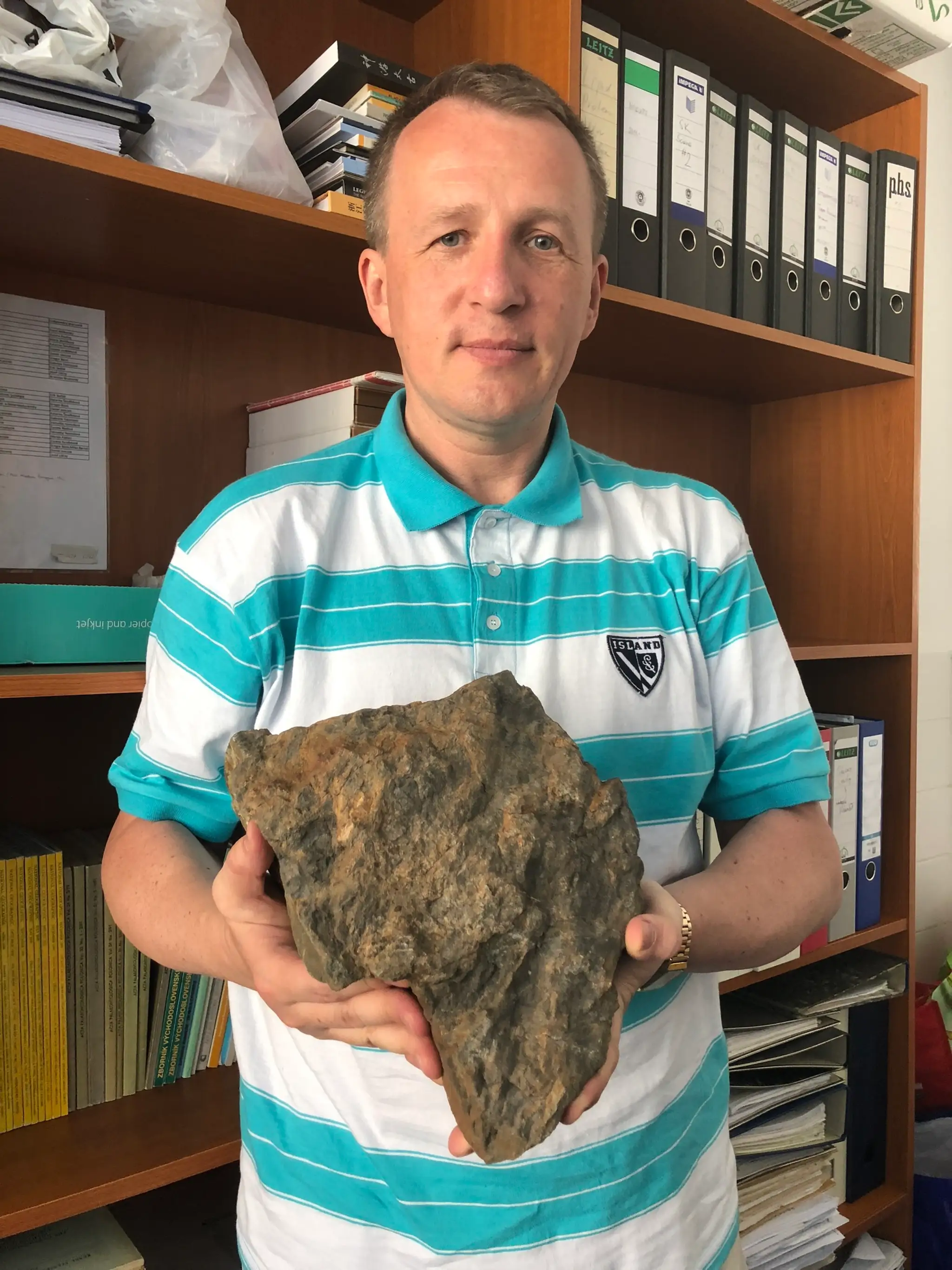 Vedec Martin Kundrát s horninou, na ktorej sa zachovali odliatky stôp dinosaurov.