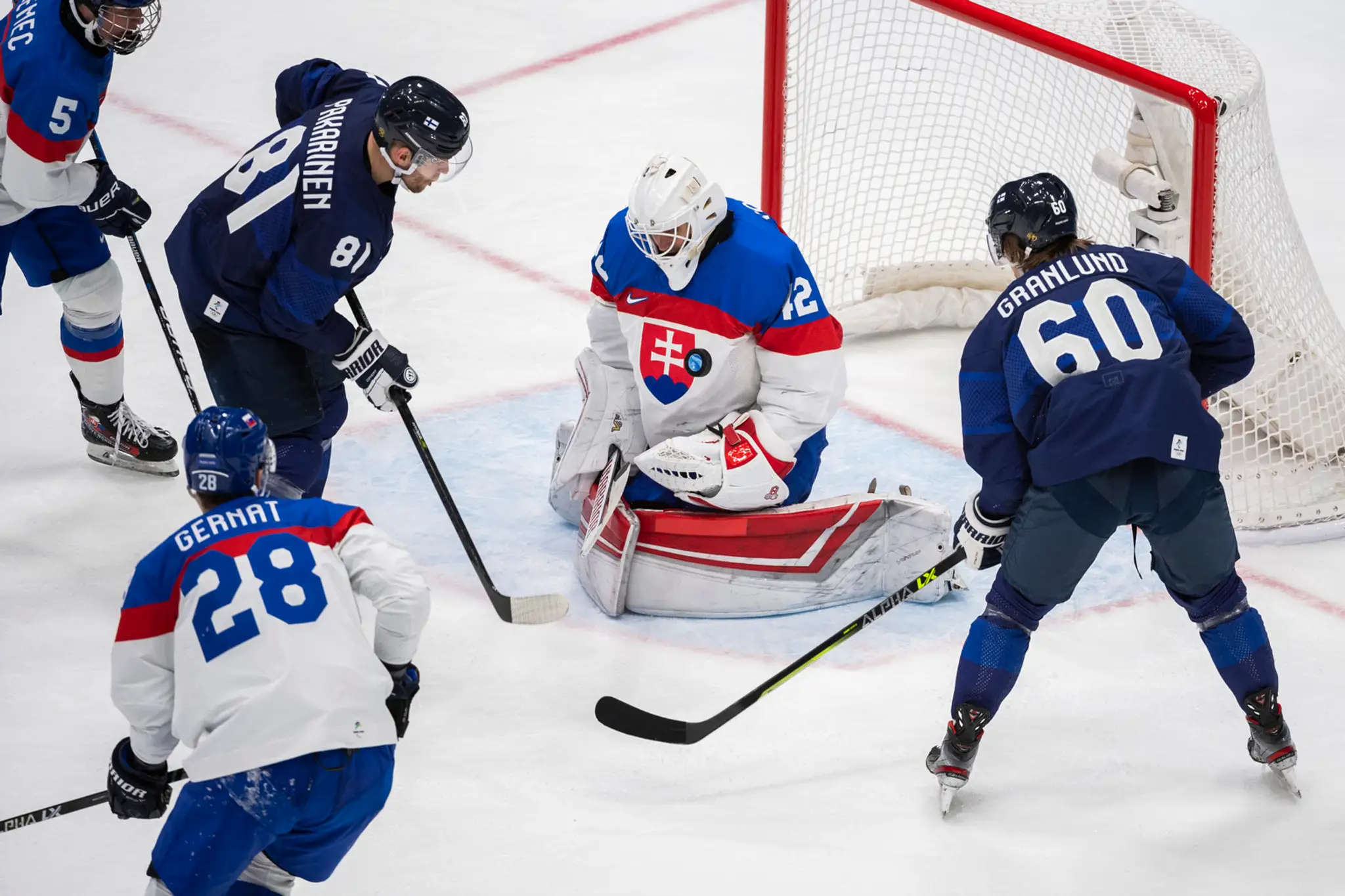 Zľava Fíni Iiro Pakarinen a Markus Granlund pred slovenským gólmanom Branislavom Konrádom na ZOH 2022.
