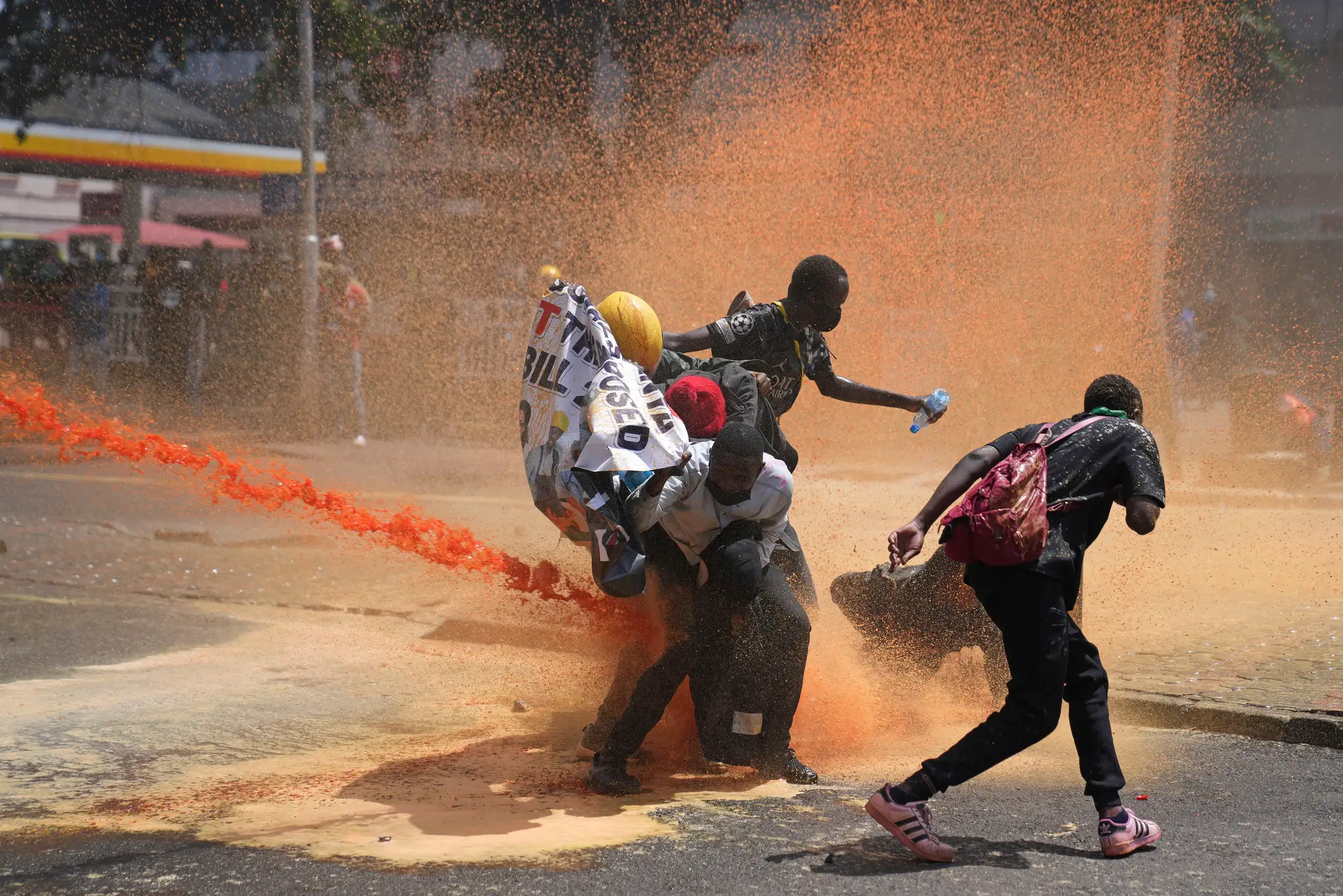 Demonštranti utekajú pred vodným delom, ktoré používa polícia počas protestu proti zavedeniu nových daní v centre Nairobi