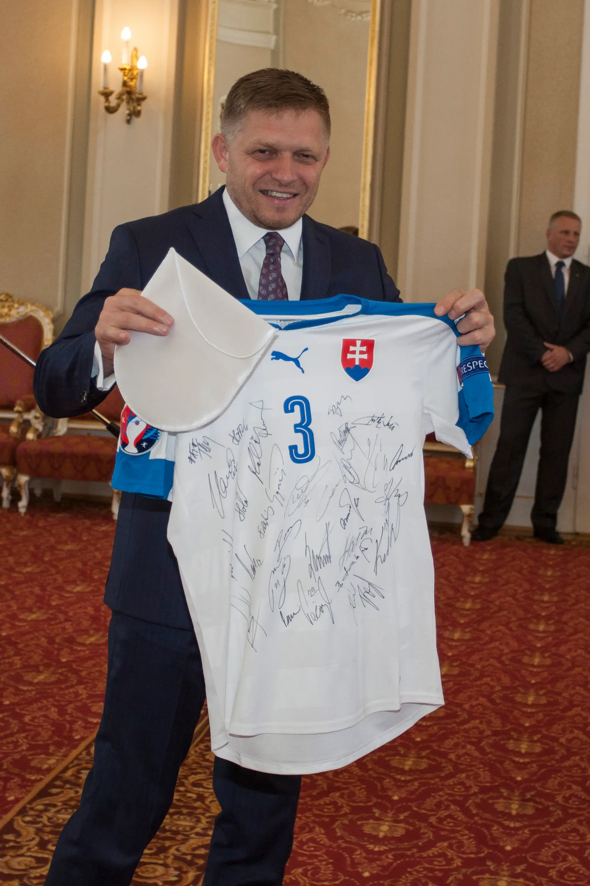 Predseda vlády SR Robert Fico ukazuje dres slovenskej futbalovej reprezentácie s podpismi hráčov.
