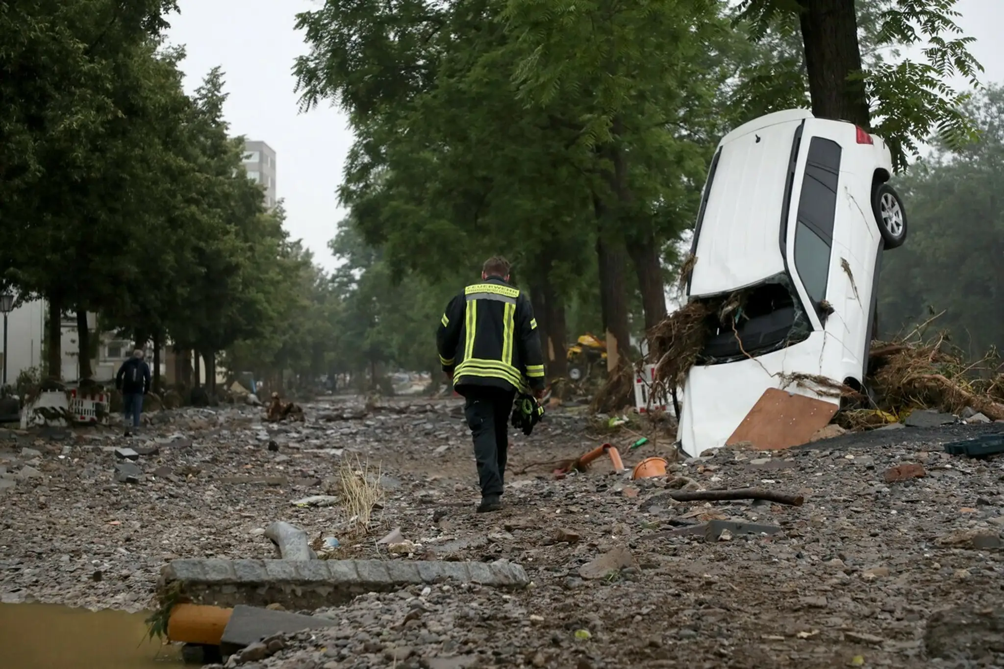 Hasič prechádza okolo vraku auta na ulici v povodňami zdevastovanom meste Bad Neuenahr-Ahrweiler.
