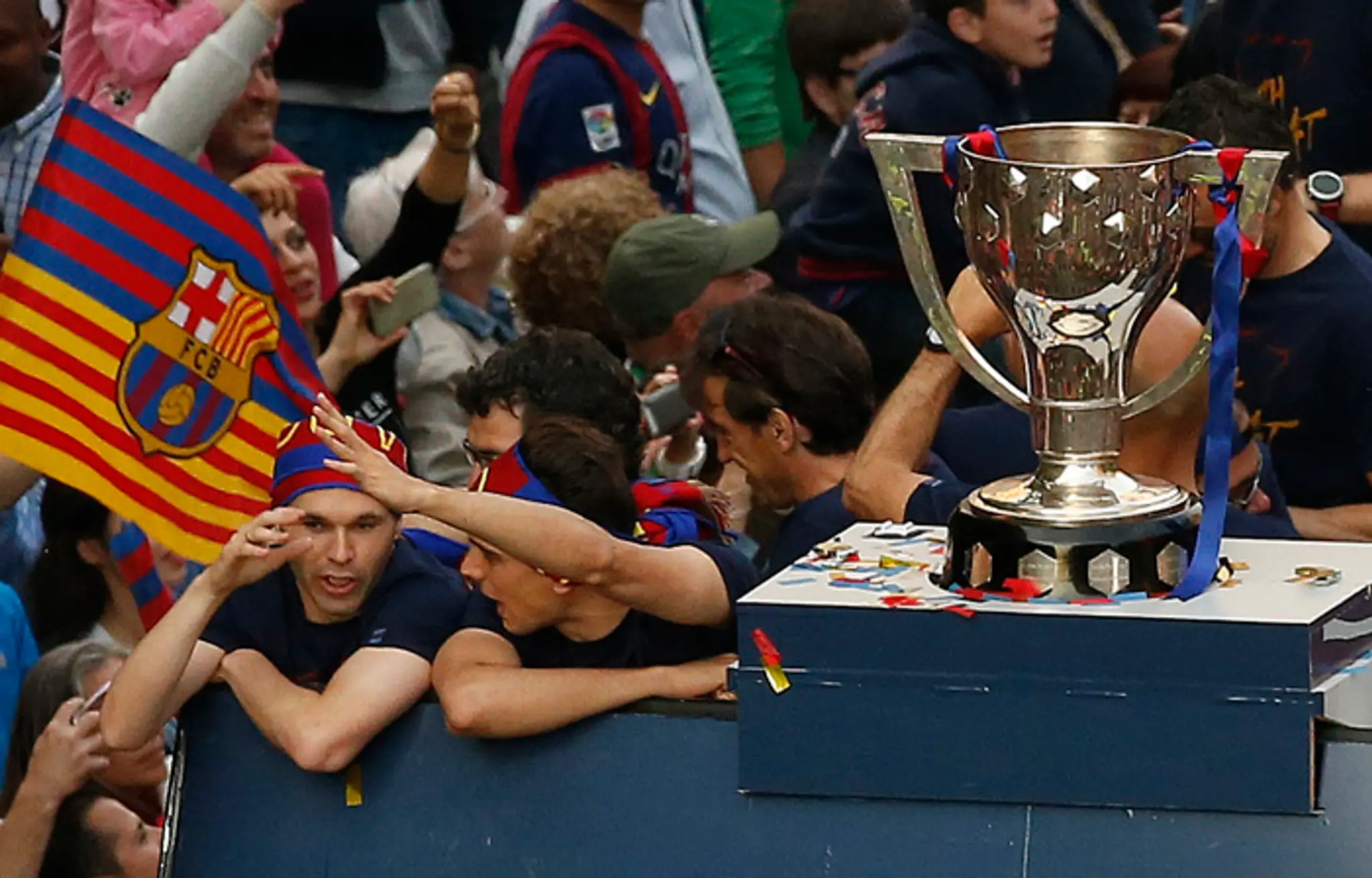 Andres Iniesta (vľavo) oslavuje na streche otvoreného autobusu ligový titul v uliciach Barcelony.